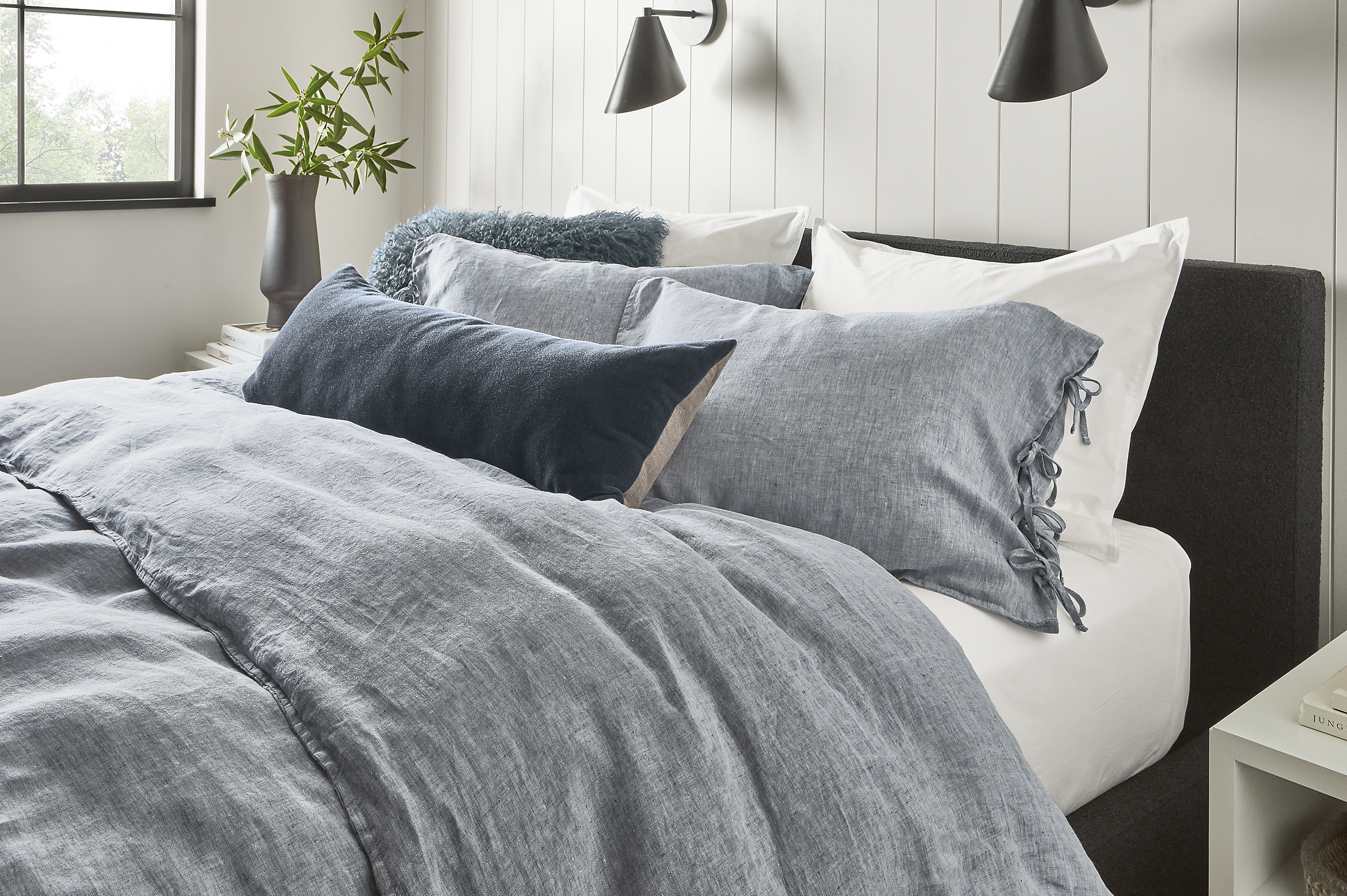 detail of bed with relaxed linen shams, duvet cover, signature percale sheets, mohair throw pillow.