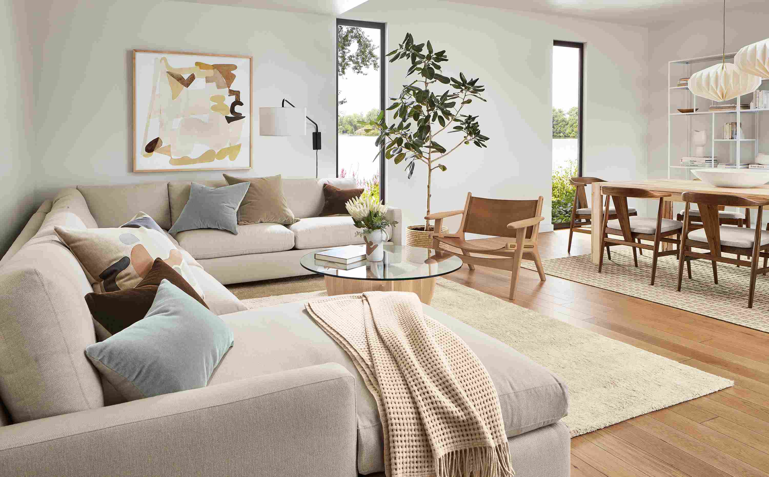 Living room with linger sectional, lars lounge chair in rye on red oak and sellare cognac leather, sanders table in salt and Jen Garrido artwork.