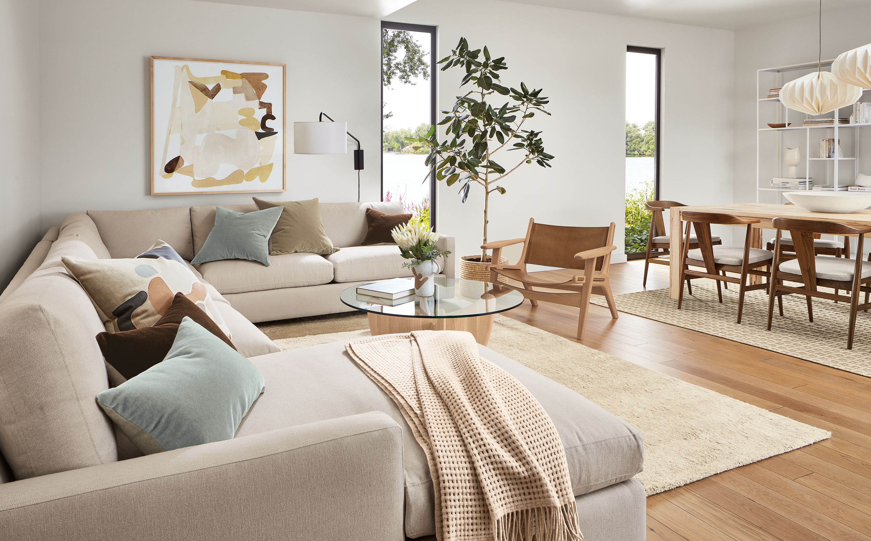 Living room with linger sectional, lars lounge chair in rye on red oak and sellare cognac leather, sanders table in salt and Jen Garrido artwork.