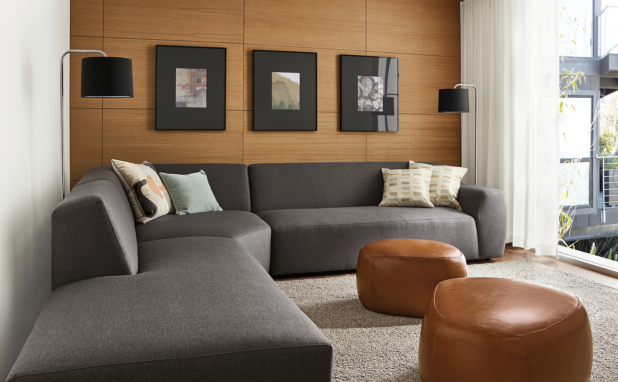 Living area with Linville three-piece sectional in Gino charcoal fabric and two Asher ottomans in Vento cognac leather.