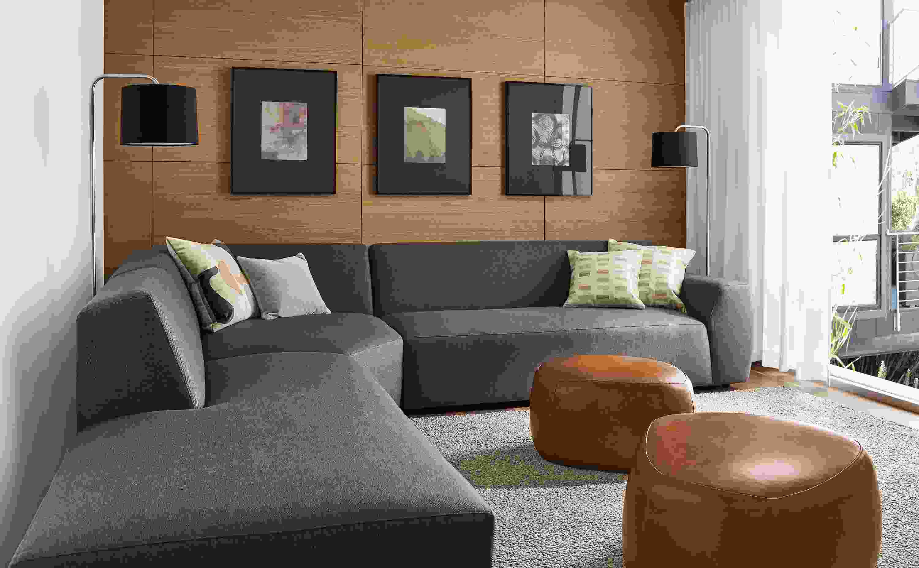 Living area with Linville three-piece sectional in Gino charcoal fabric and two Asher ottomans in Vento cognac leather.