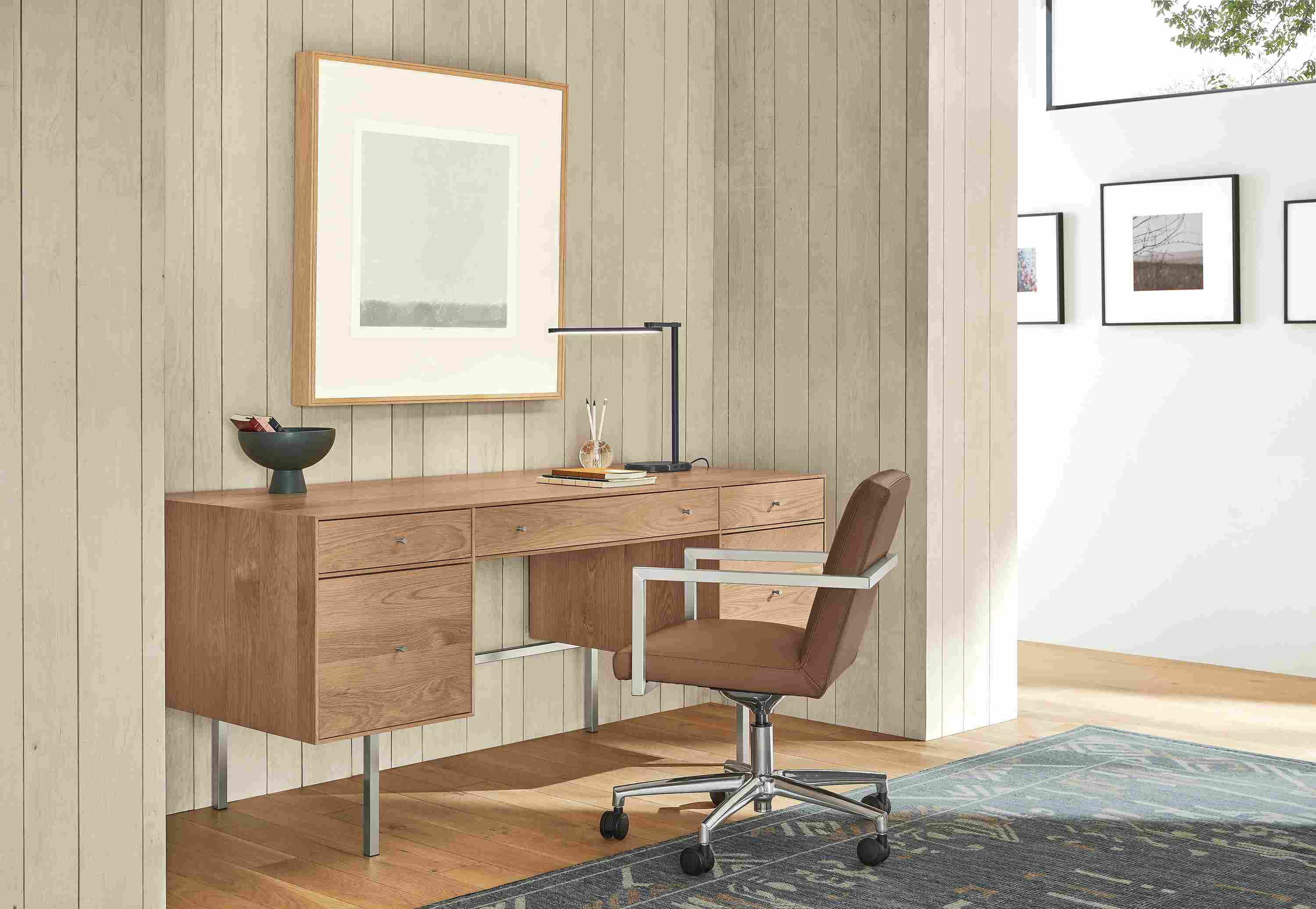 Office area with Lira office chair in Laino Cognac leather, Hudson desk in Rye and Amira rug in Ocean.