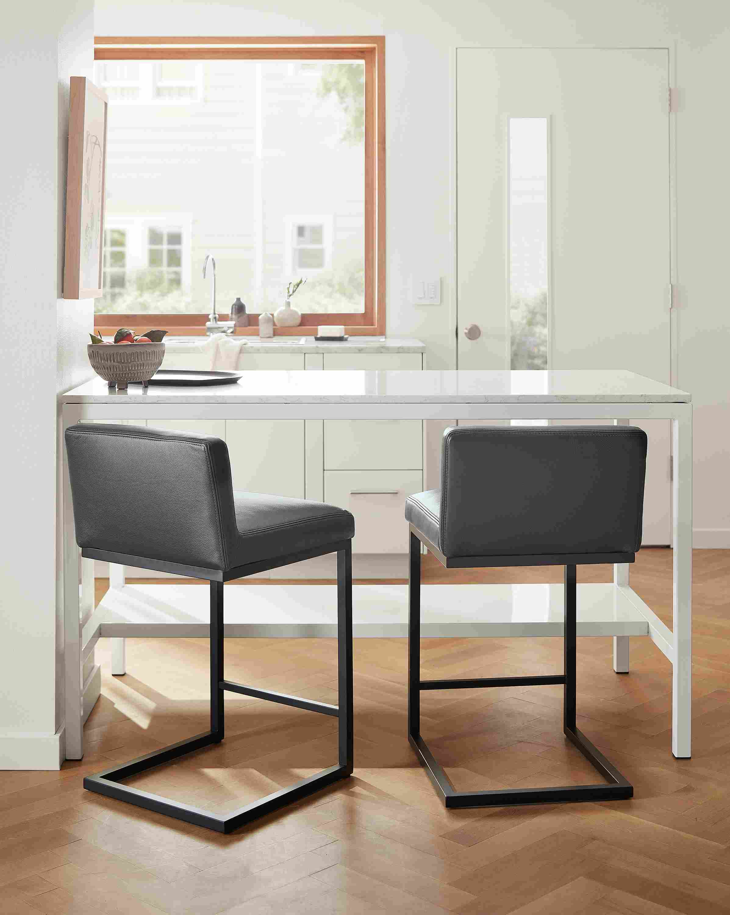 Kitchen counter with 2 lira counter stools in Laino Black leather with graphite and parsons table in white.