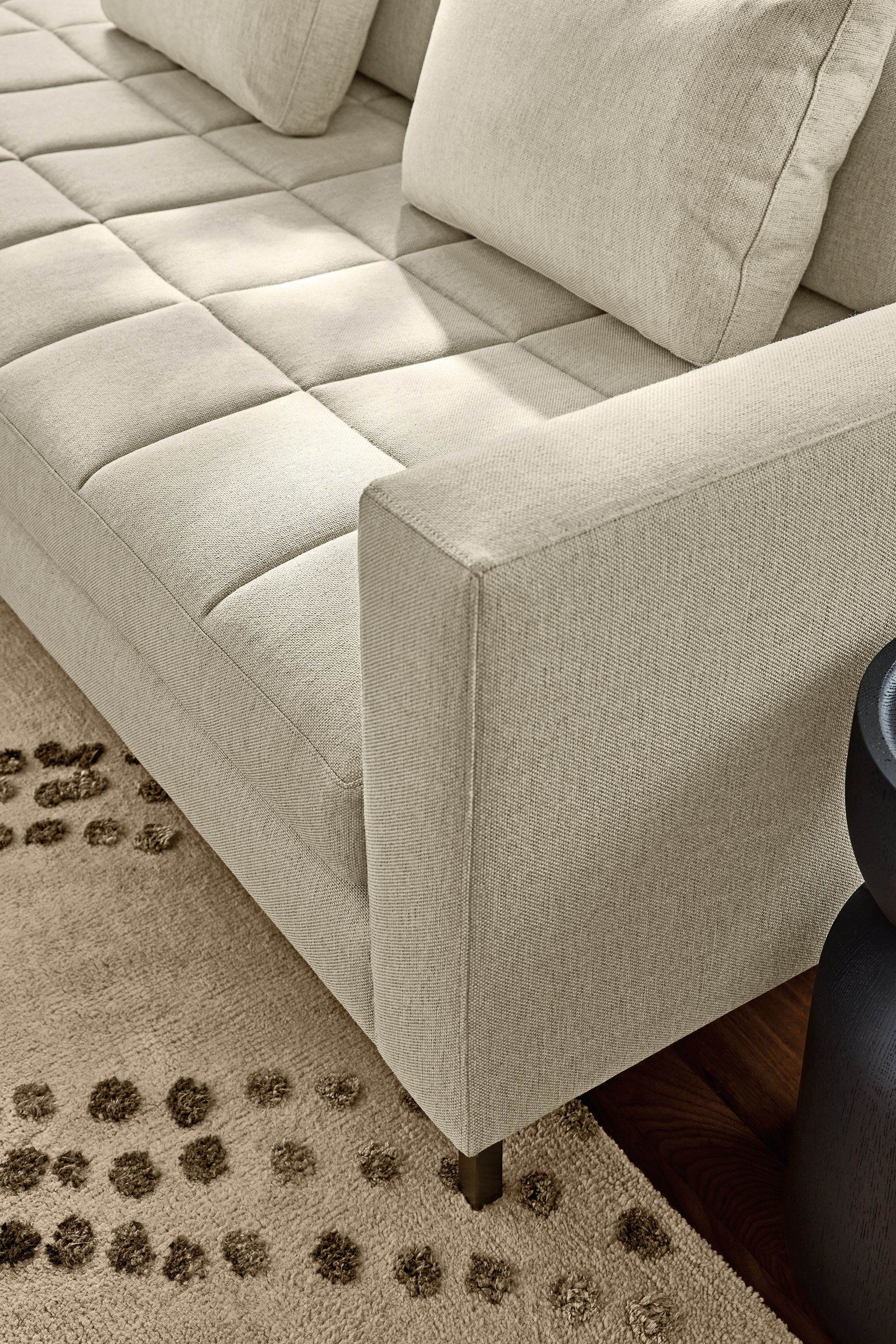 Detail of arm of a Lloyd sectional sofa in Sumner Linen and Sitara rug in Pewter.