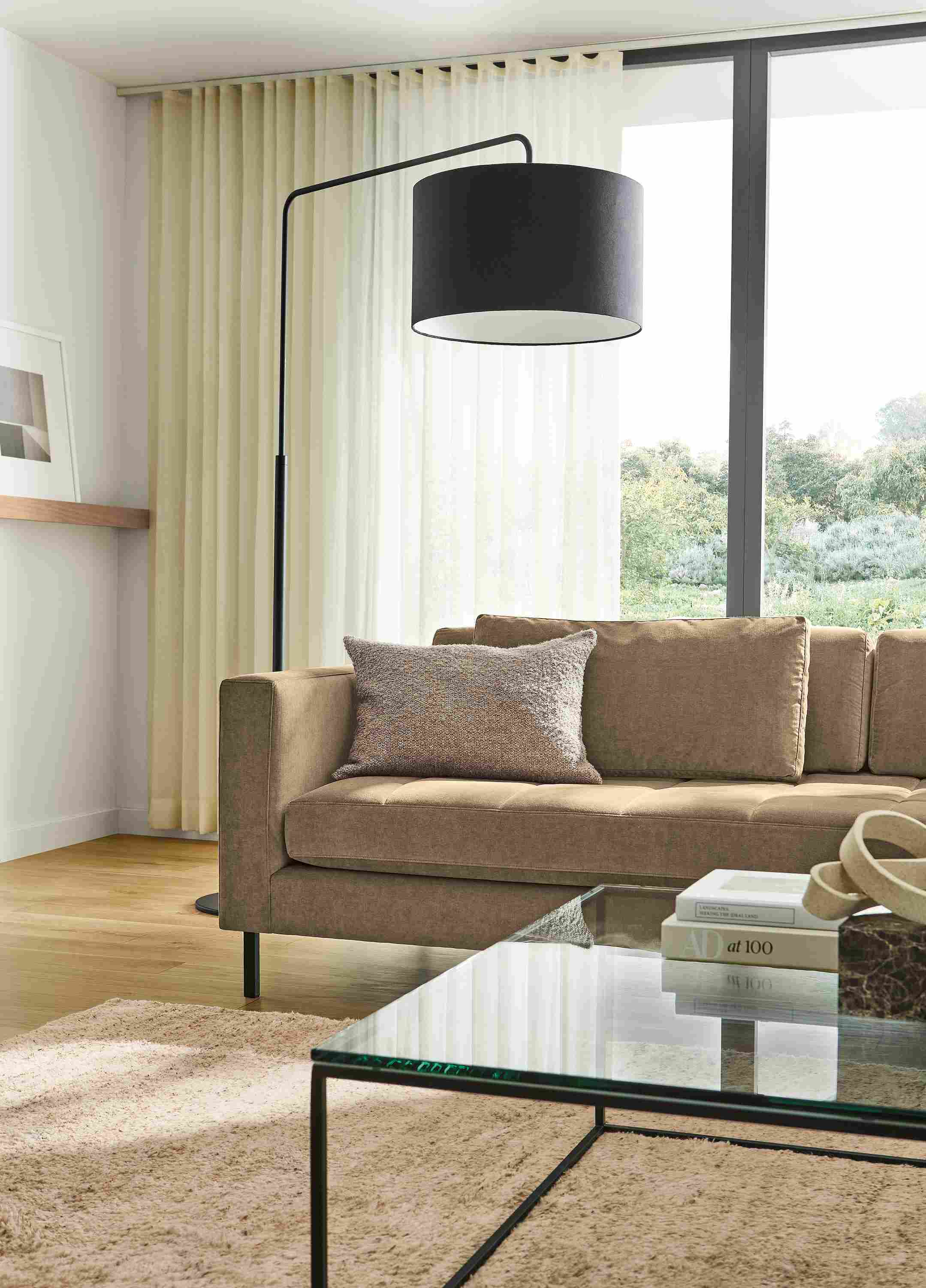 Living room with Lloyd 92-wide sofa in Windsor Otter, Tyne coffee table in clear glass and graphite and Kalindi rug in Flax.