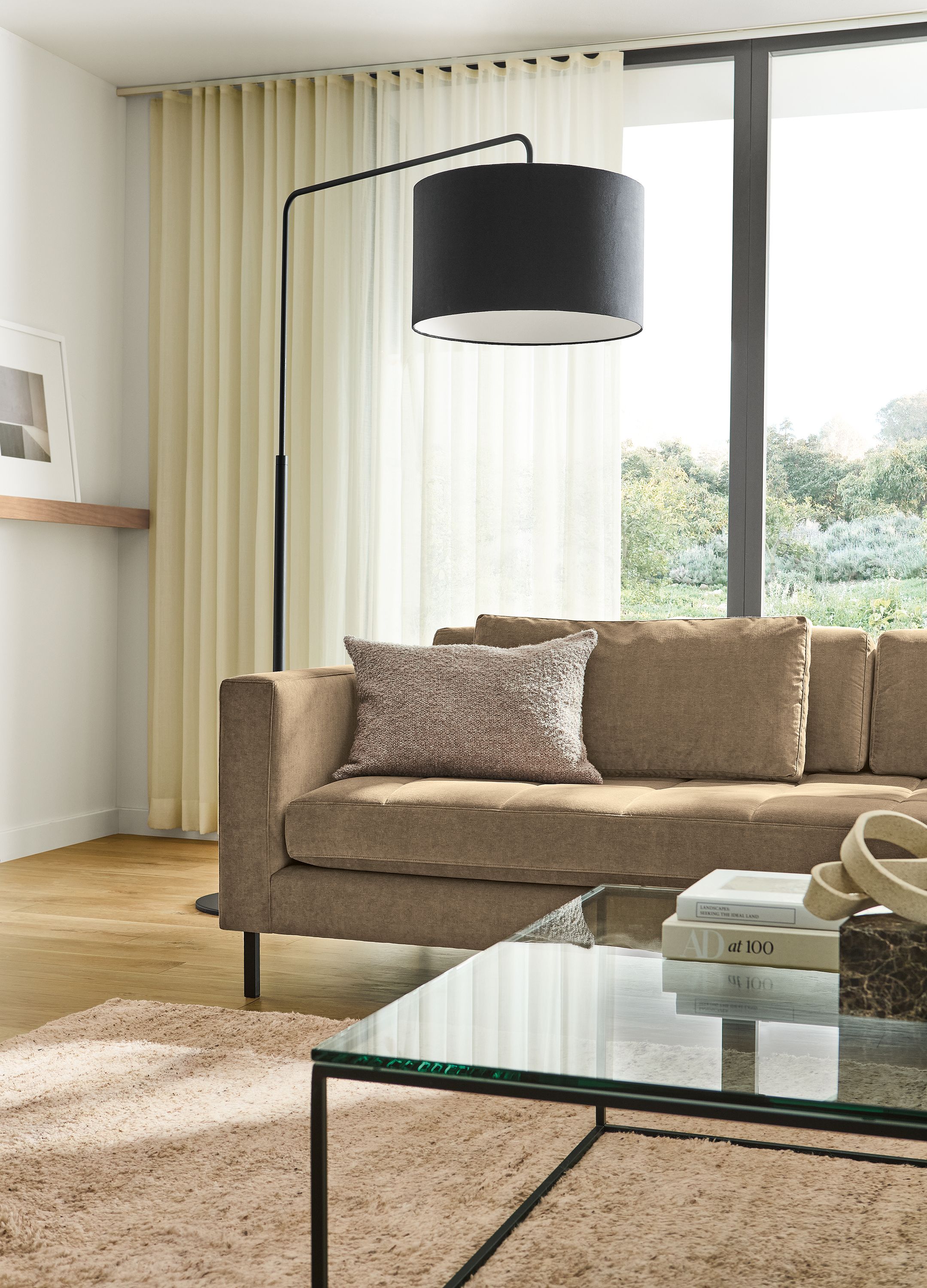 Living room with Lloyd 92-wide sofa in Windsor Otter, Tyne coffee table in clear glass and graphite and Kalindi rug in Flax.