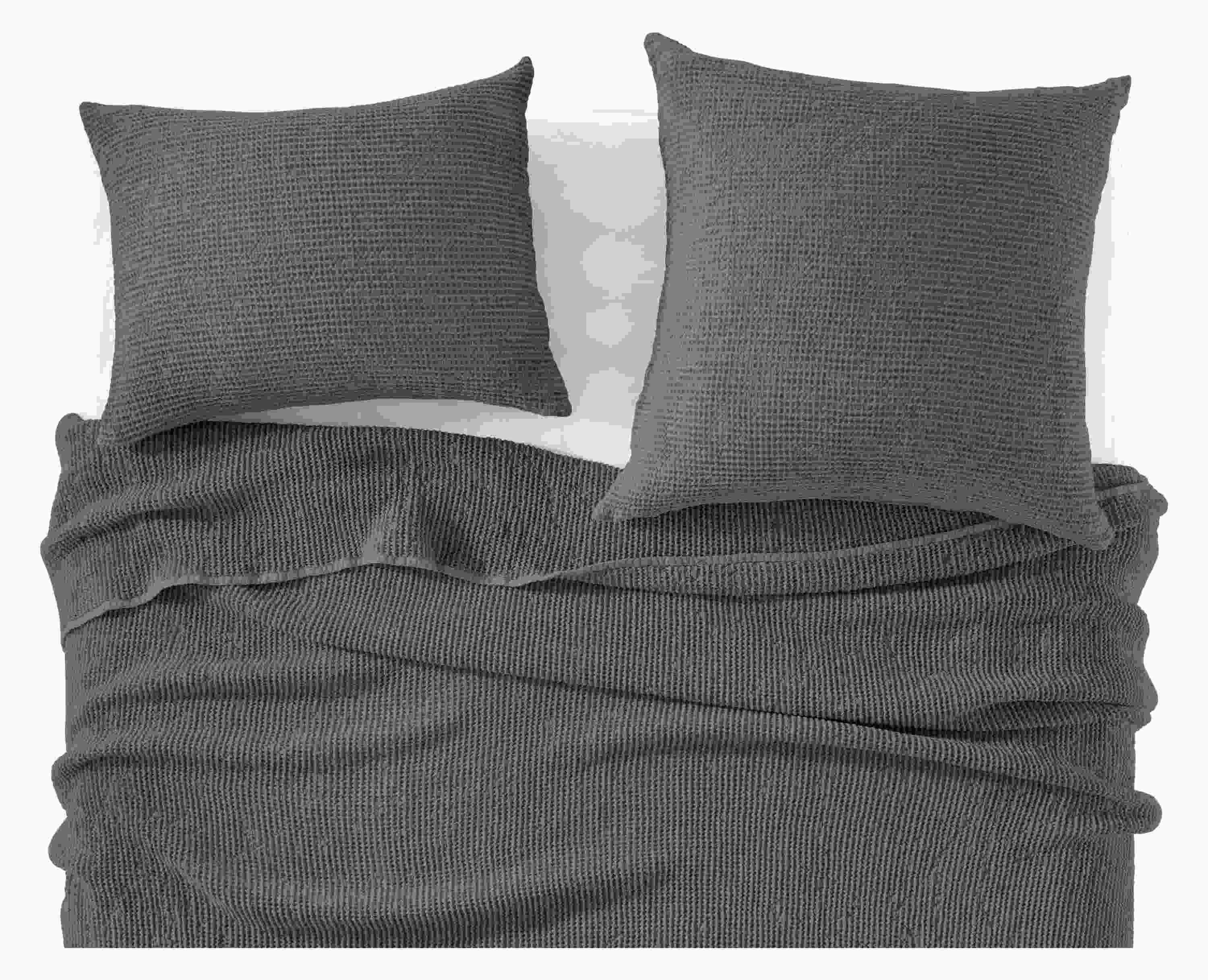 detail of loren coverlet and shams in charcoal on bed.
