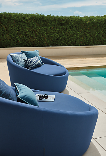 Two Lunar 57-inch swivel chairs in Niro Navy with various pillows in navy and ink.
