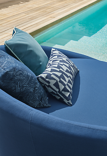 Closeup of Lunar 57-inch swivel chairs in Niro Navy with various pillows in navy and ink.