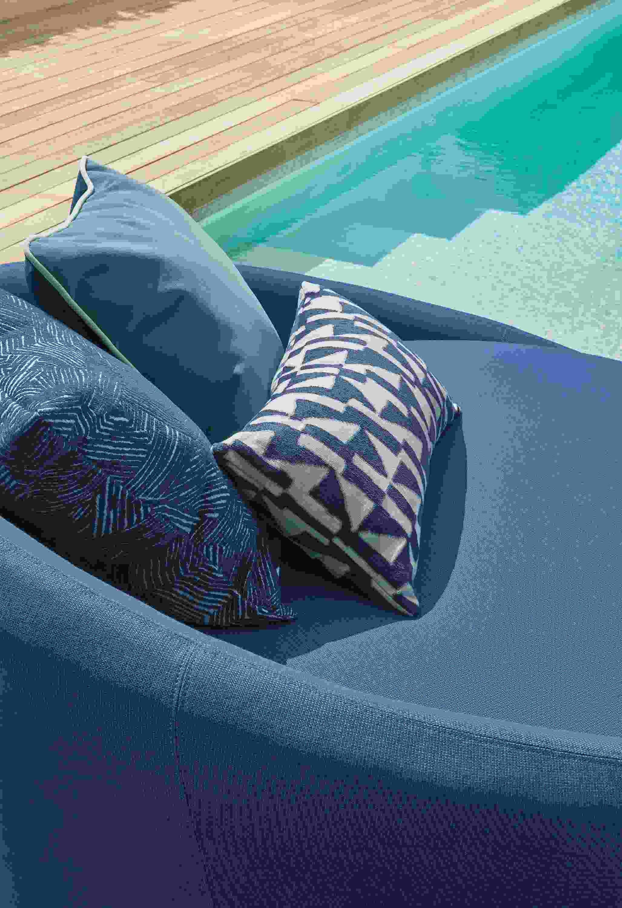 Closeup of Lunar 57-inch swivel chairs in Niro Navy with various pillows in navy and ink.
