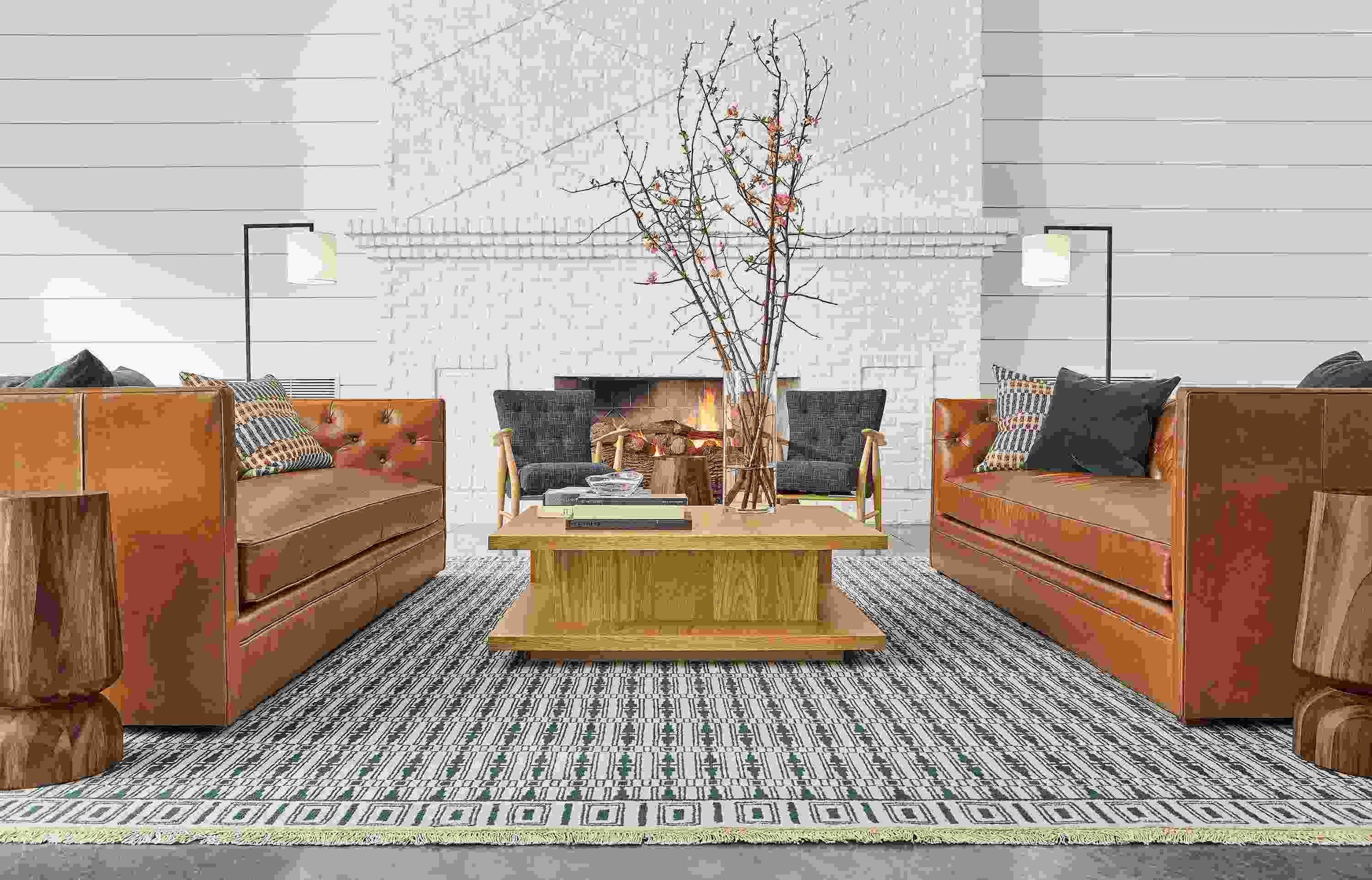 Detail of Macalester sofas in Portofino Cognac leather and Graham coffee table in white oak in lobby setting.