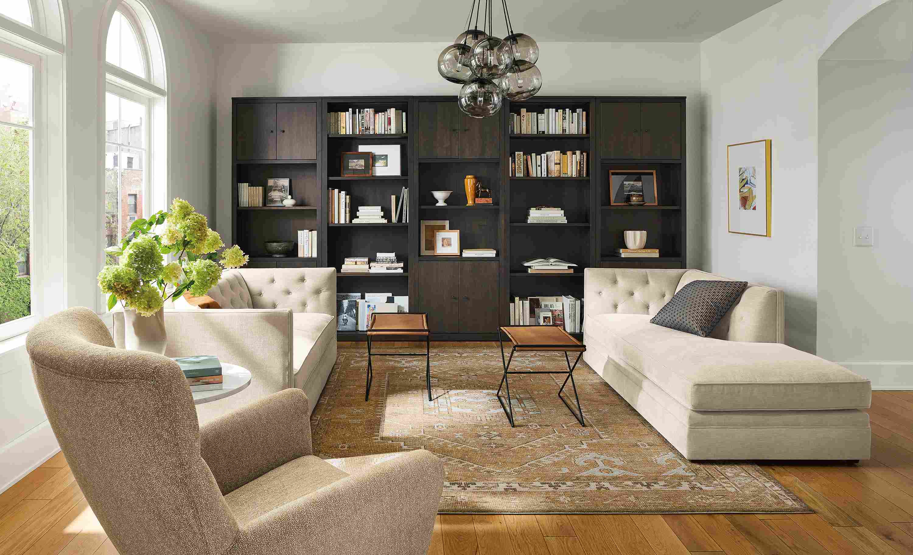 Living room with Macalester sofa and Macalester chaise, Charcoal woodwind bookcases in charcoal, and Darrah rug.