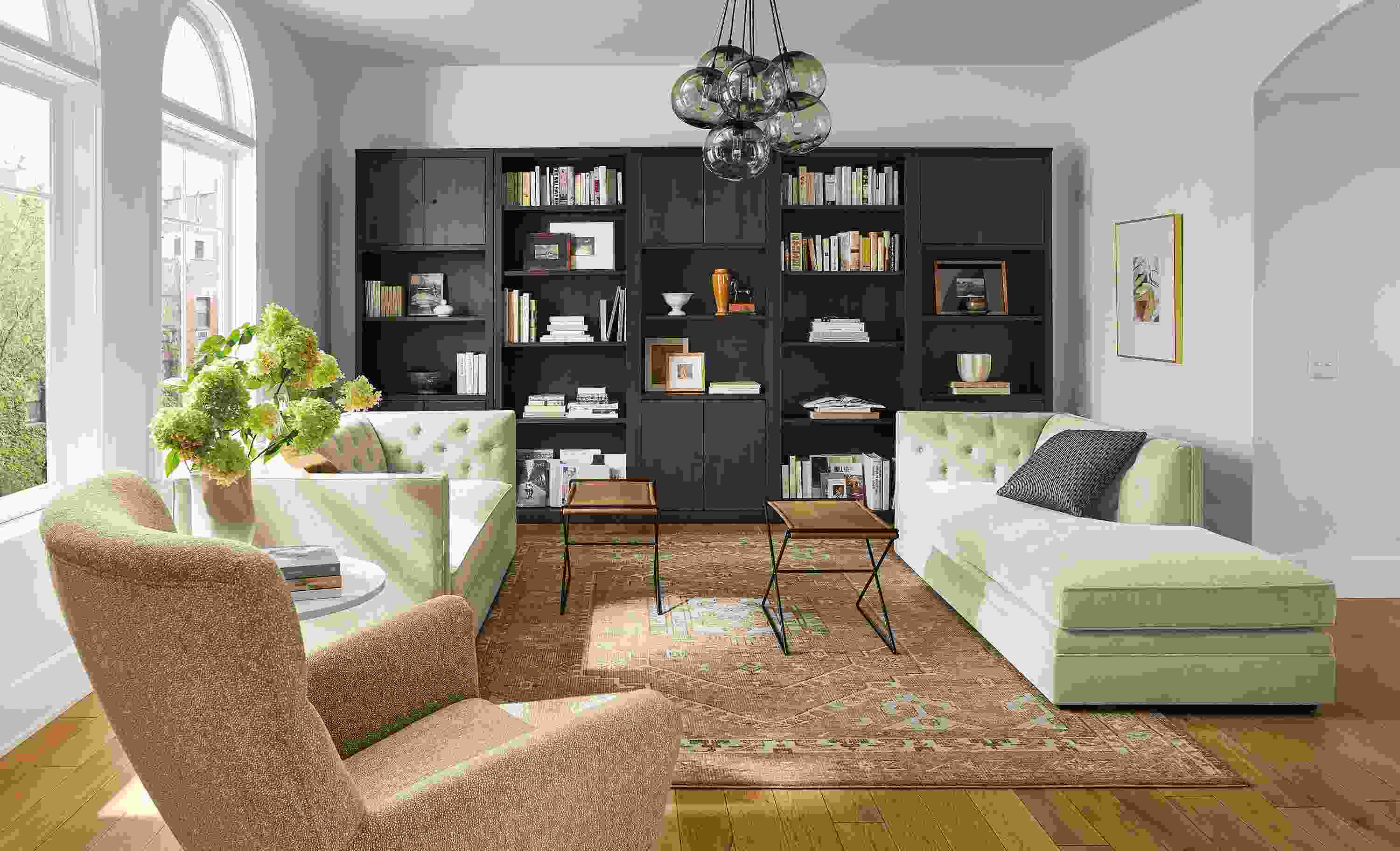 Living room with Macalester sofa and Macalester chaise, Charcoal woodwind bookcases in charcoal, and Darrah rug.