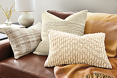 detail of mackenzie, spencer and segal pillows on sofa with colorful throw blanket