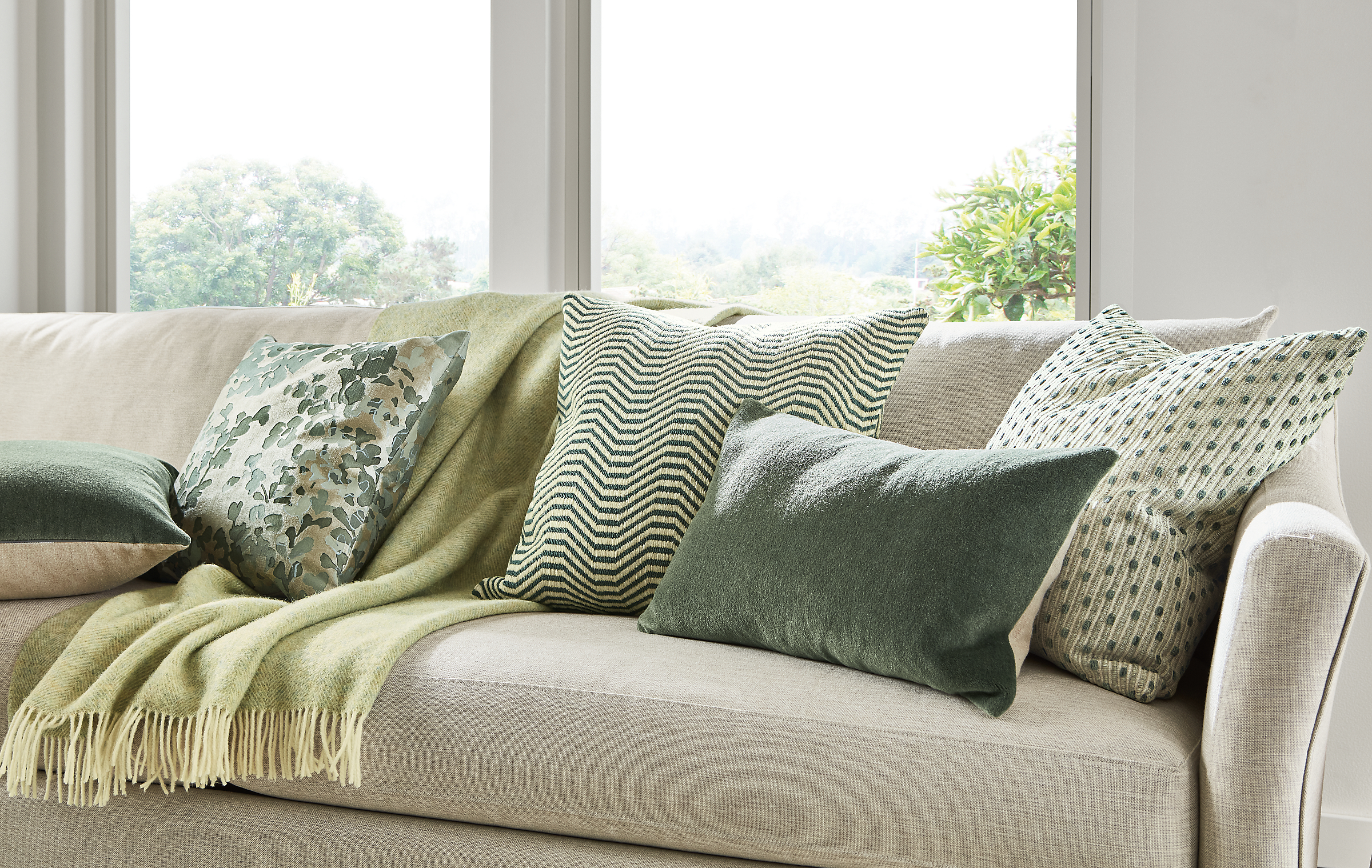 Maeve sofa in Yana natural with wool velvet pillows in olive, lines pillow in lagoon and claridge blanket in cloud.