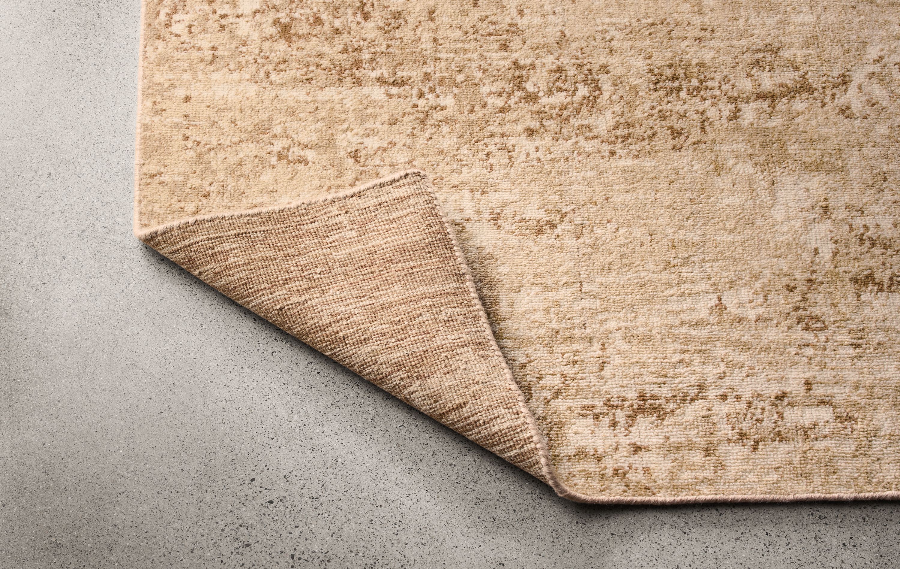 Makali 8 by 10 rug in stone shown with corner flipped up to show underside of rug.