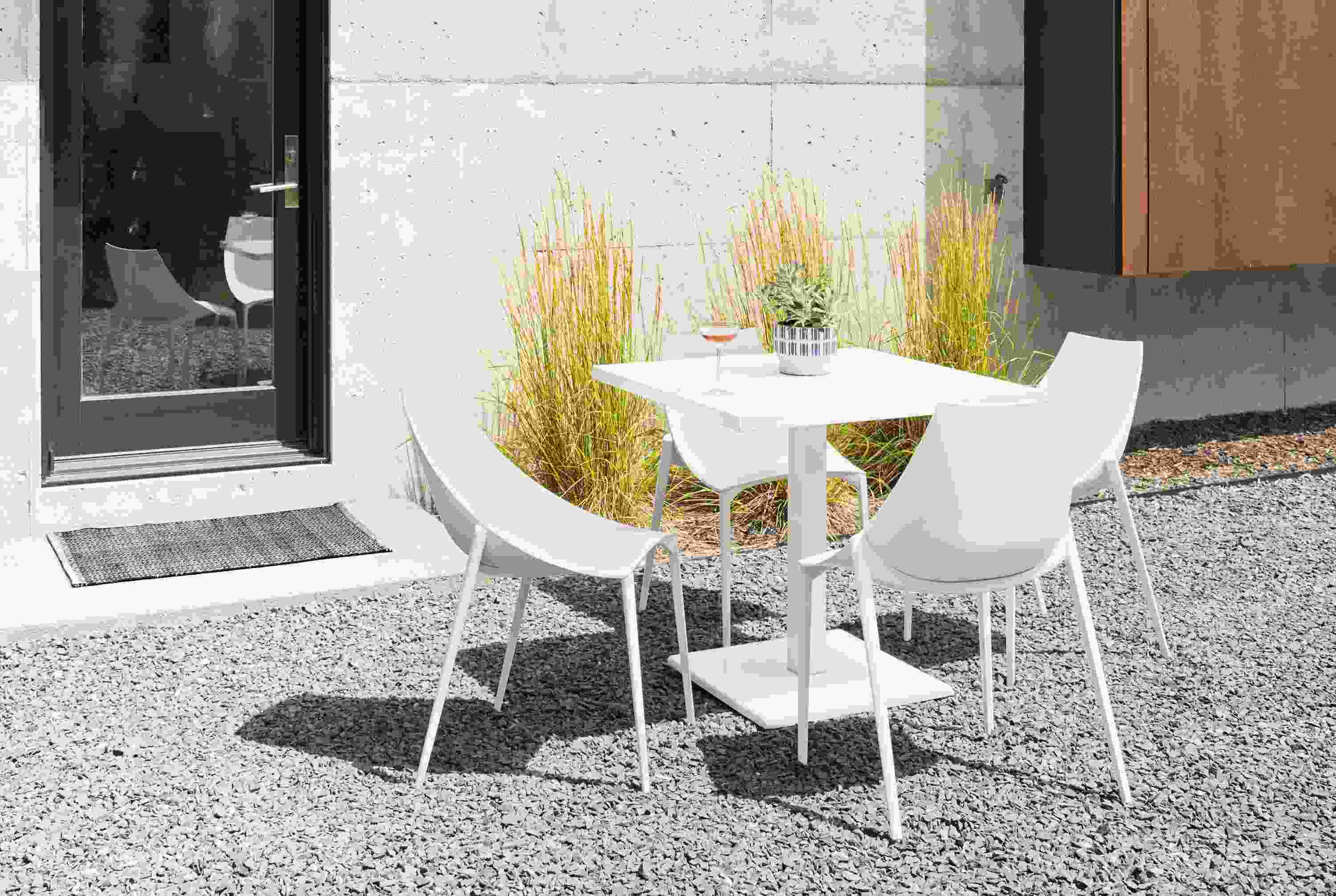 Stone patio with Maris square table and hoop chairs in white.