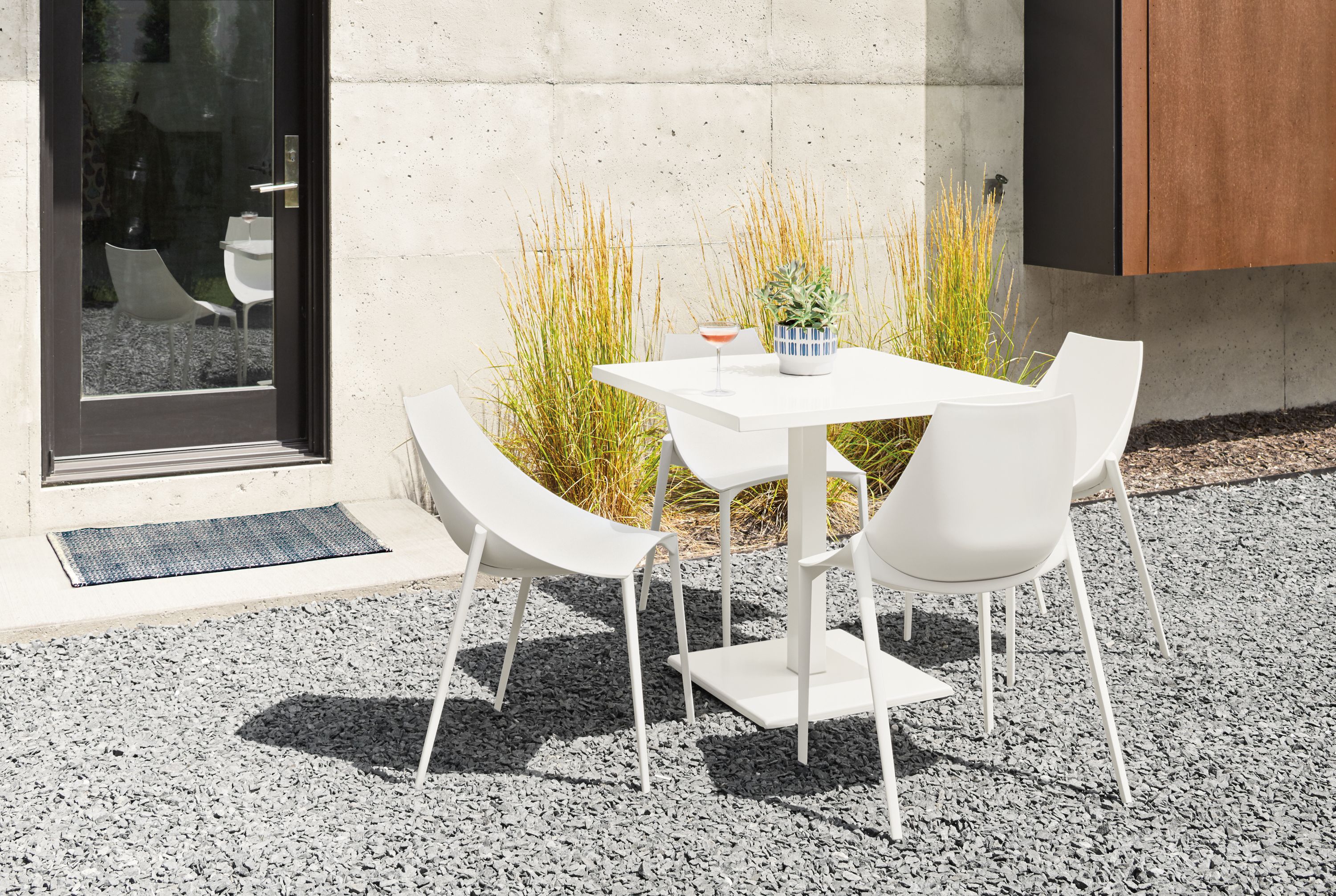 Stone patio with Maris square table and hoop chairs in white.