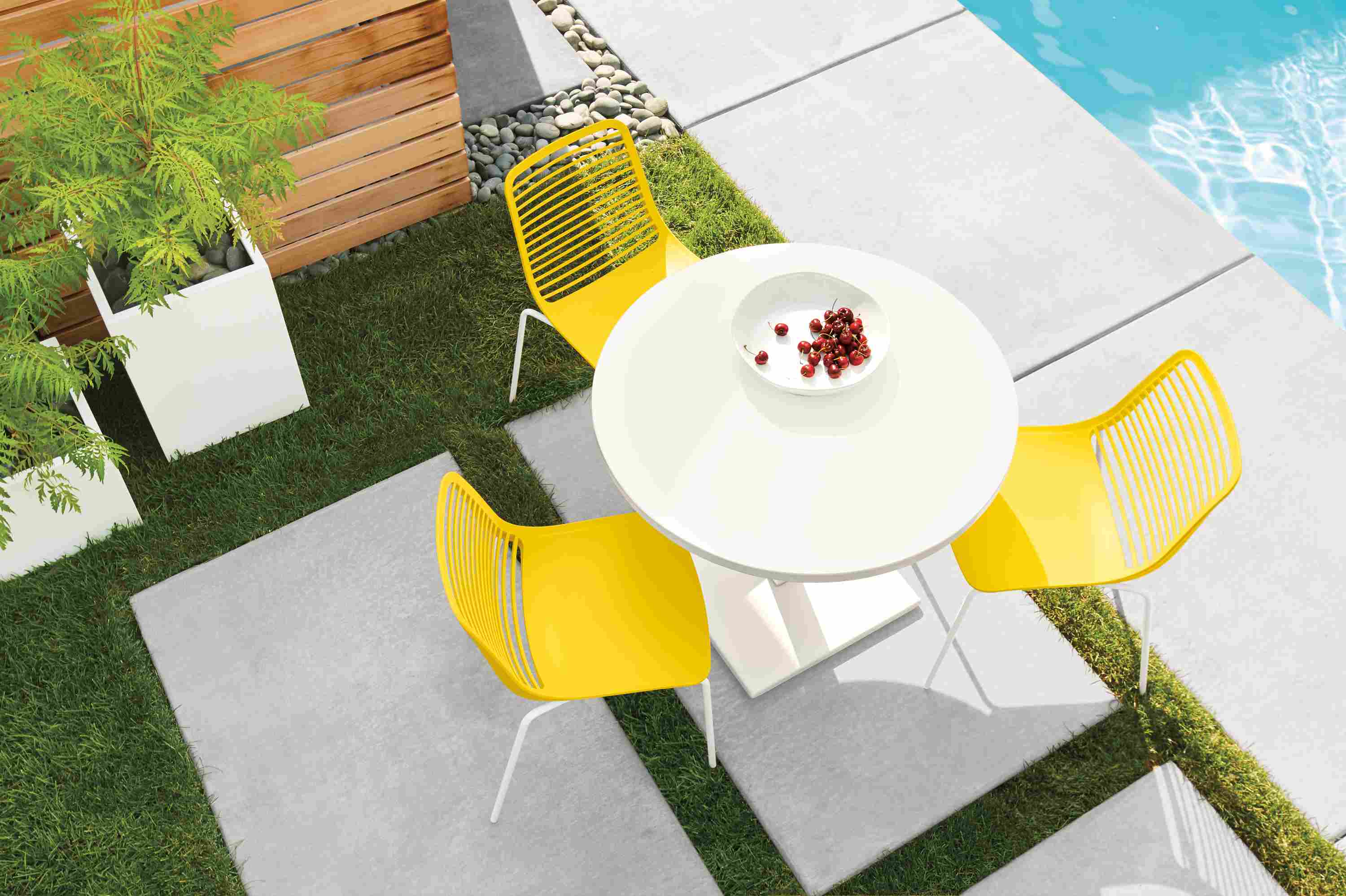Detail of Maris round table in white and 3 mini side chairs in yellow.