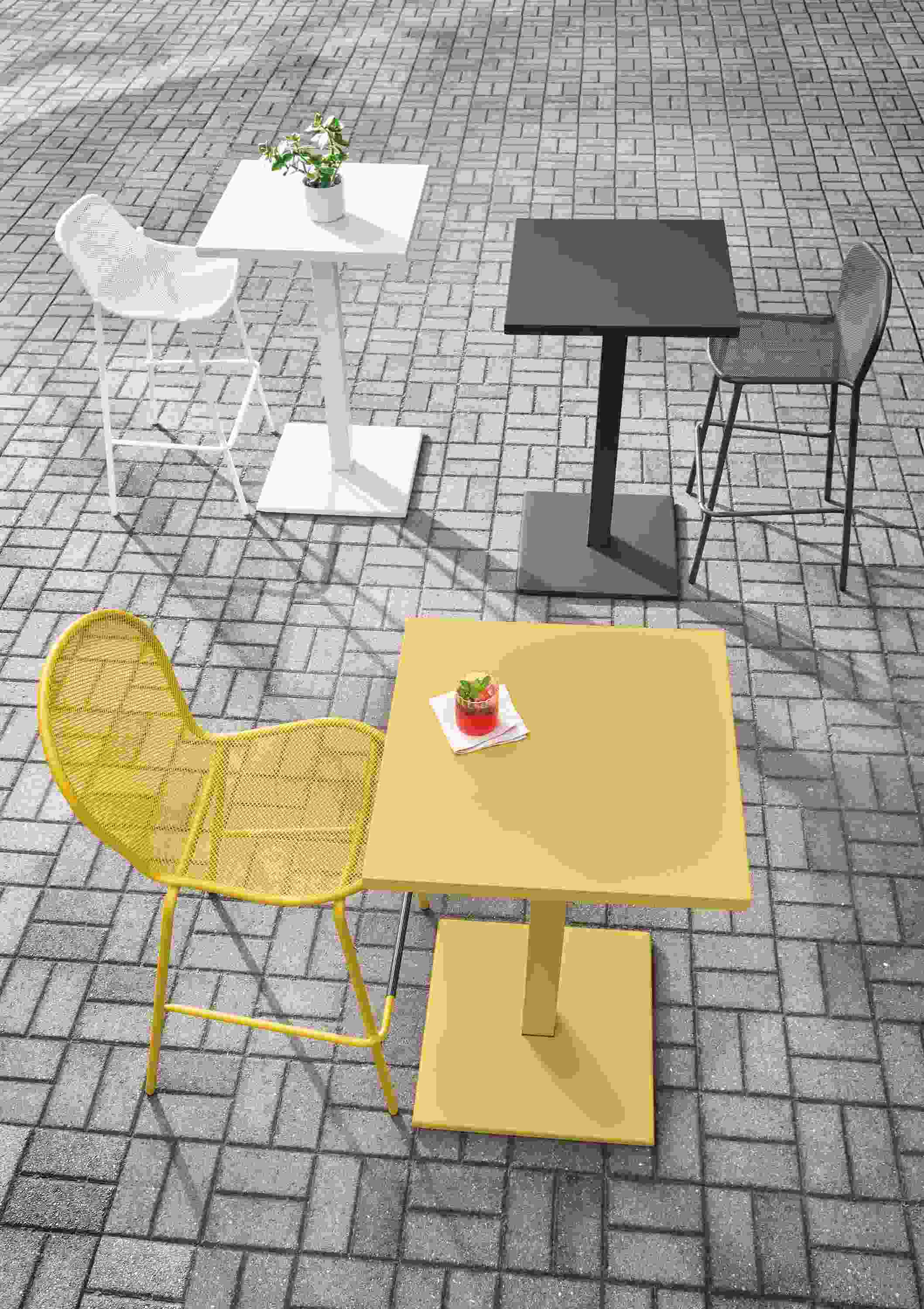 Maris square tables in saffron, graphite and white on a large brick patio.