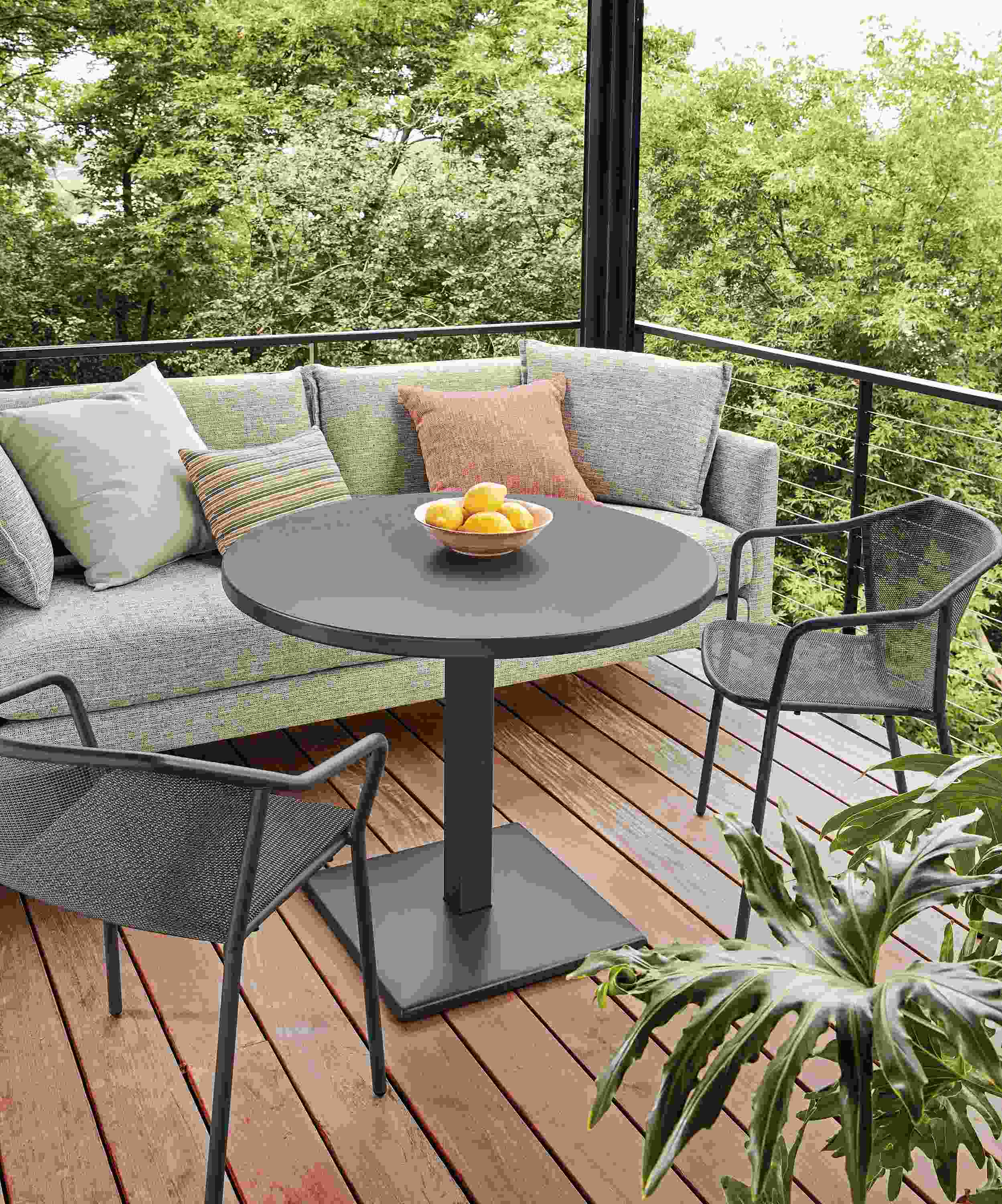 Detail of Maris outdoor round patio table and Palm sofa on a home deck.