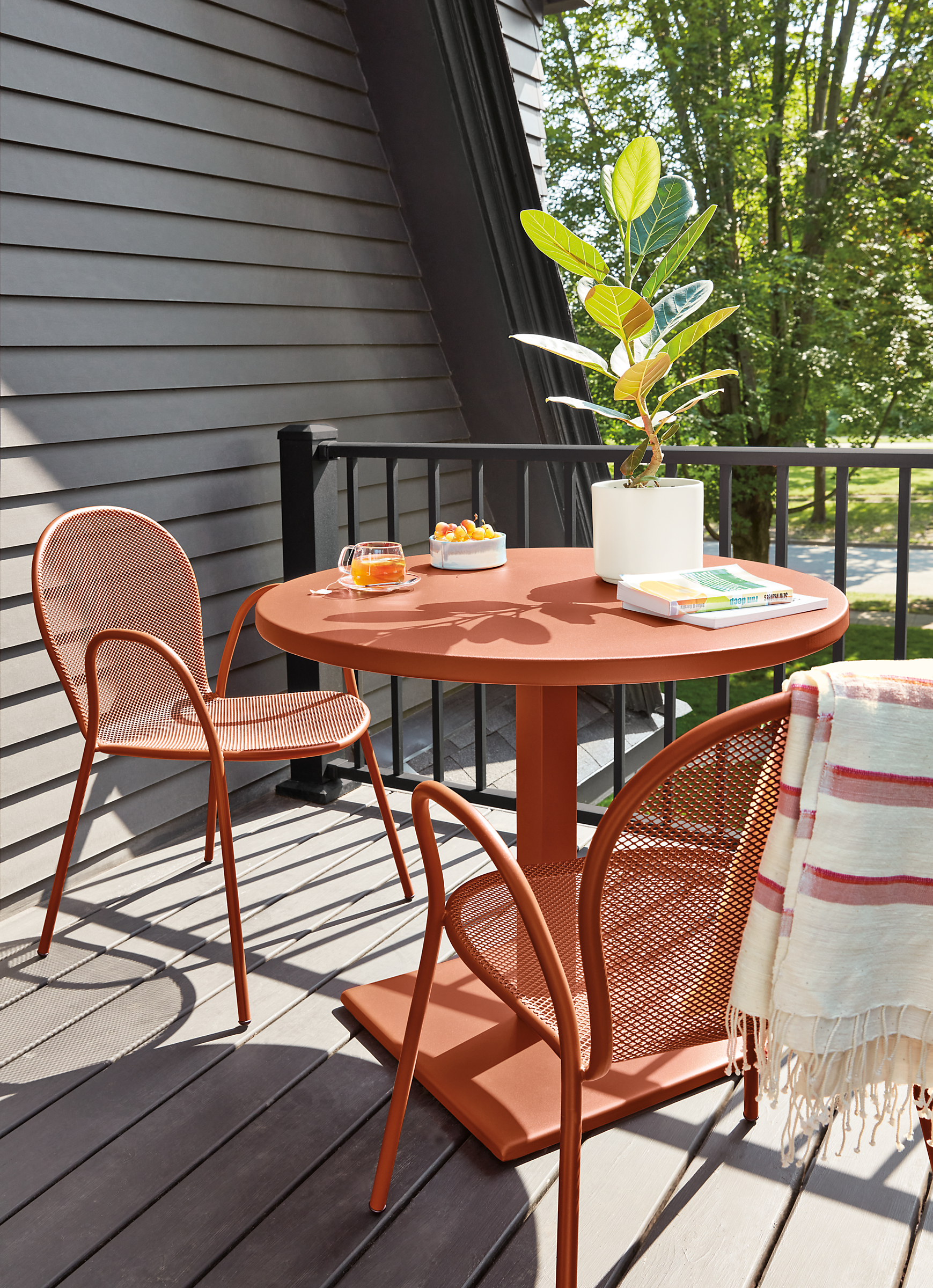 Outdoor deck with Maris round table and two Rio chairs in Cognac.