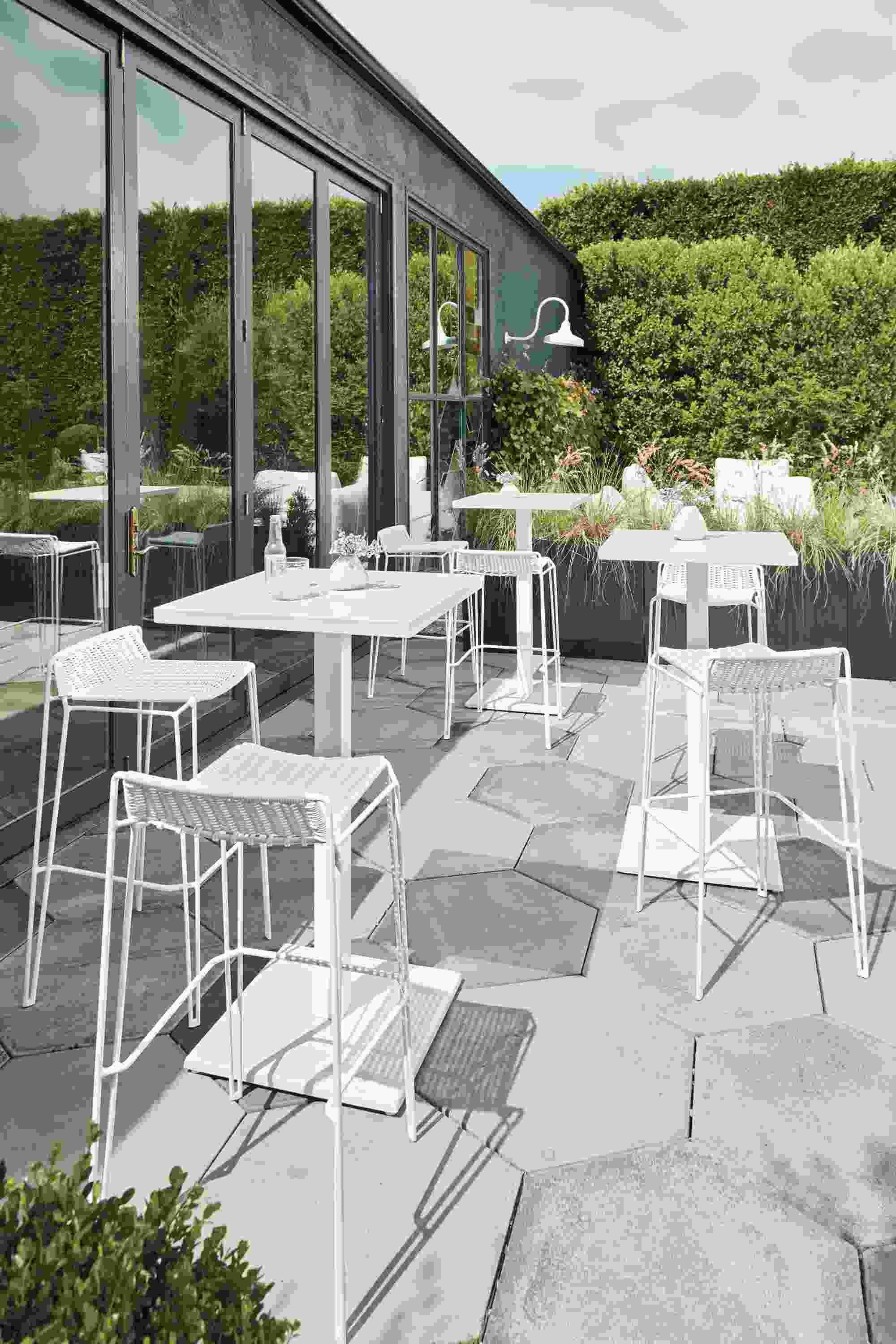 Patio with Maris square bar tables and Penelope bar stools all in white.