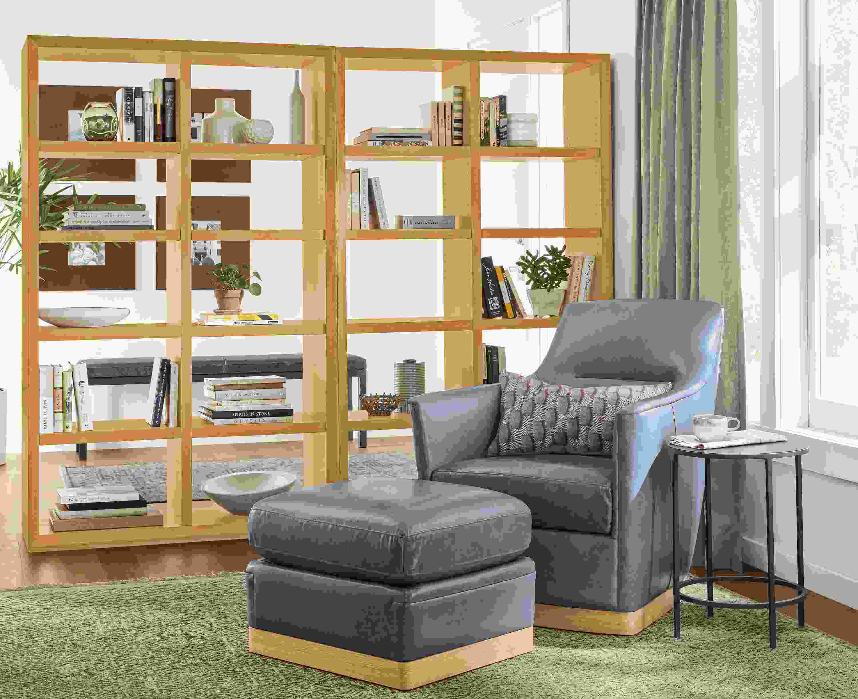 Detail of Markus chair in Vento cadet leather with matching ottoman, next to Lennox bookcases.