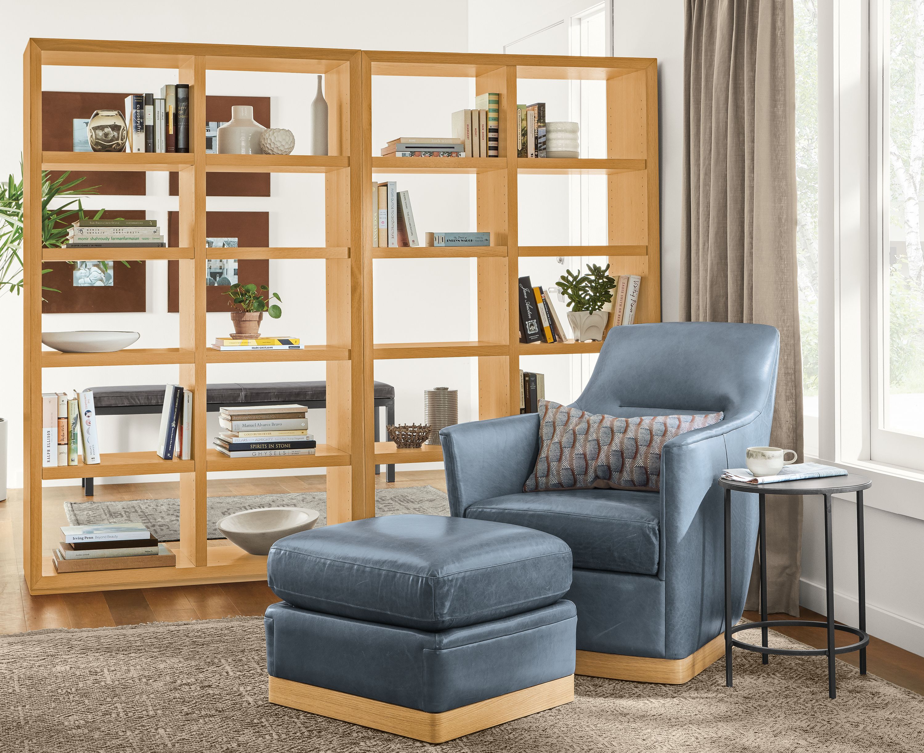 Detail of Markus chair in Vento cadet leather with matching ottoman, next to Lennox bookcases.