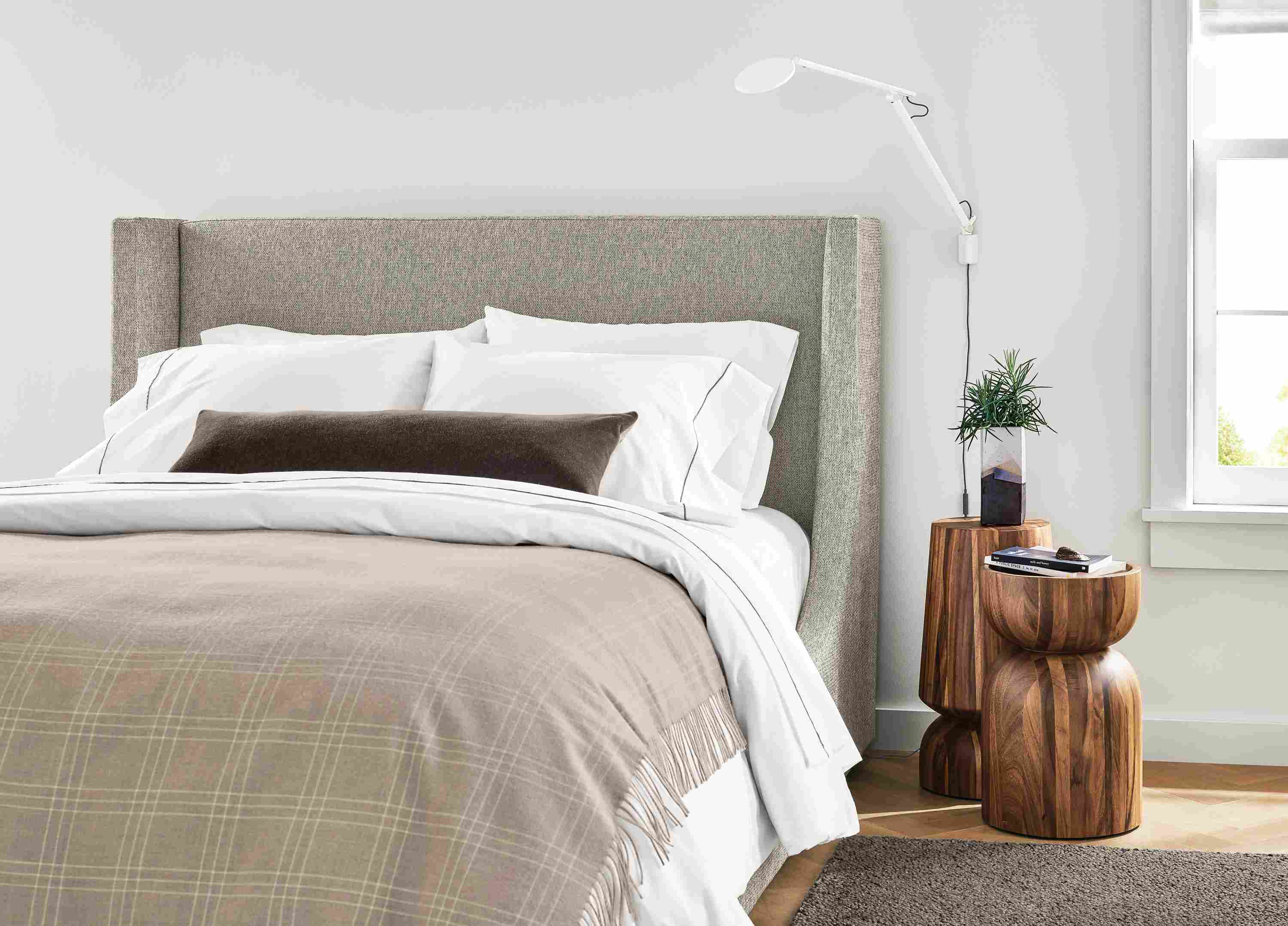 Detail of Marlo queen storage bed in Tepic Cement, 2 Nyla tables in conacaste wood and Arden rug in putty.