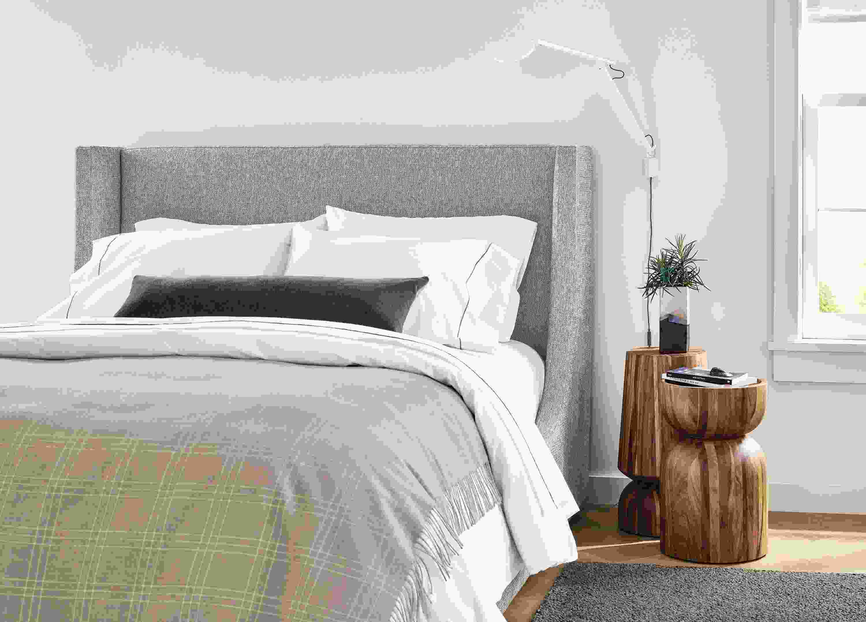 Detail of Marlo queen storage bed in Tepic Cement, 2 Nyla tables in conacaste wood and Arden rug in putty.