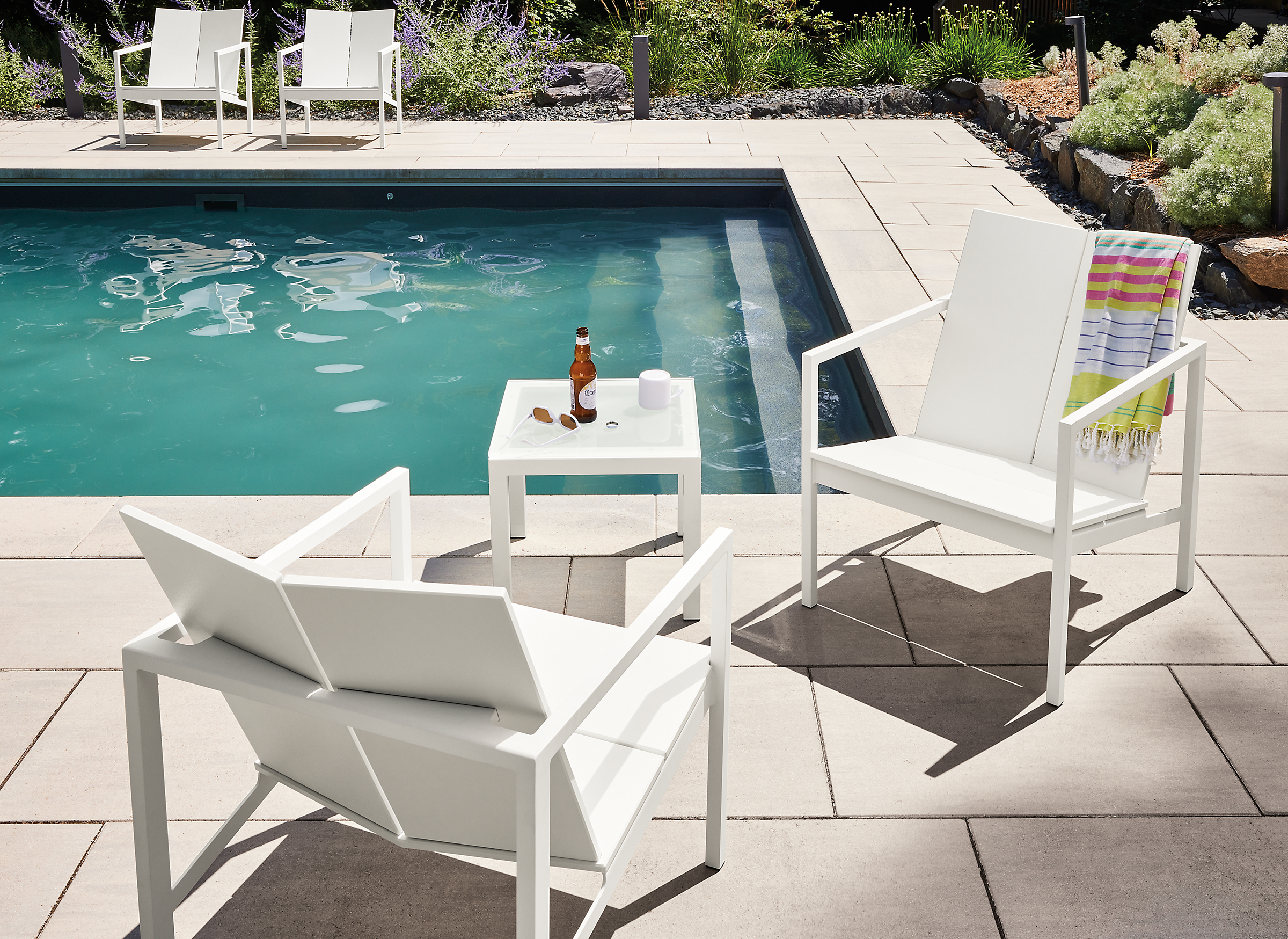 Outdoor space with mattix chairs by pool and a small parsons coffee table.