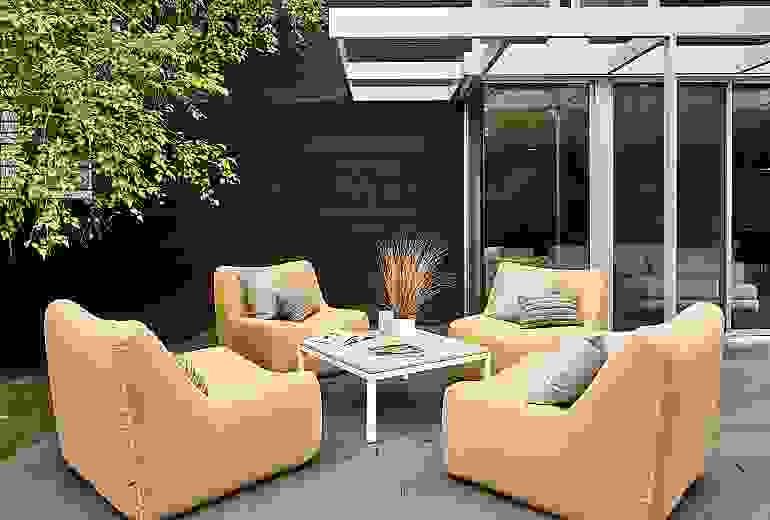 Outdoor setting with 4 Maya Swivel Chairs in Sunbrella Canvas Saffron and a Parsons 36 inch square outdoor coffee table.