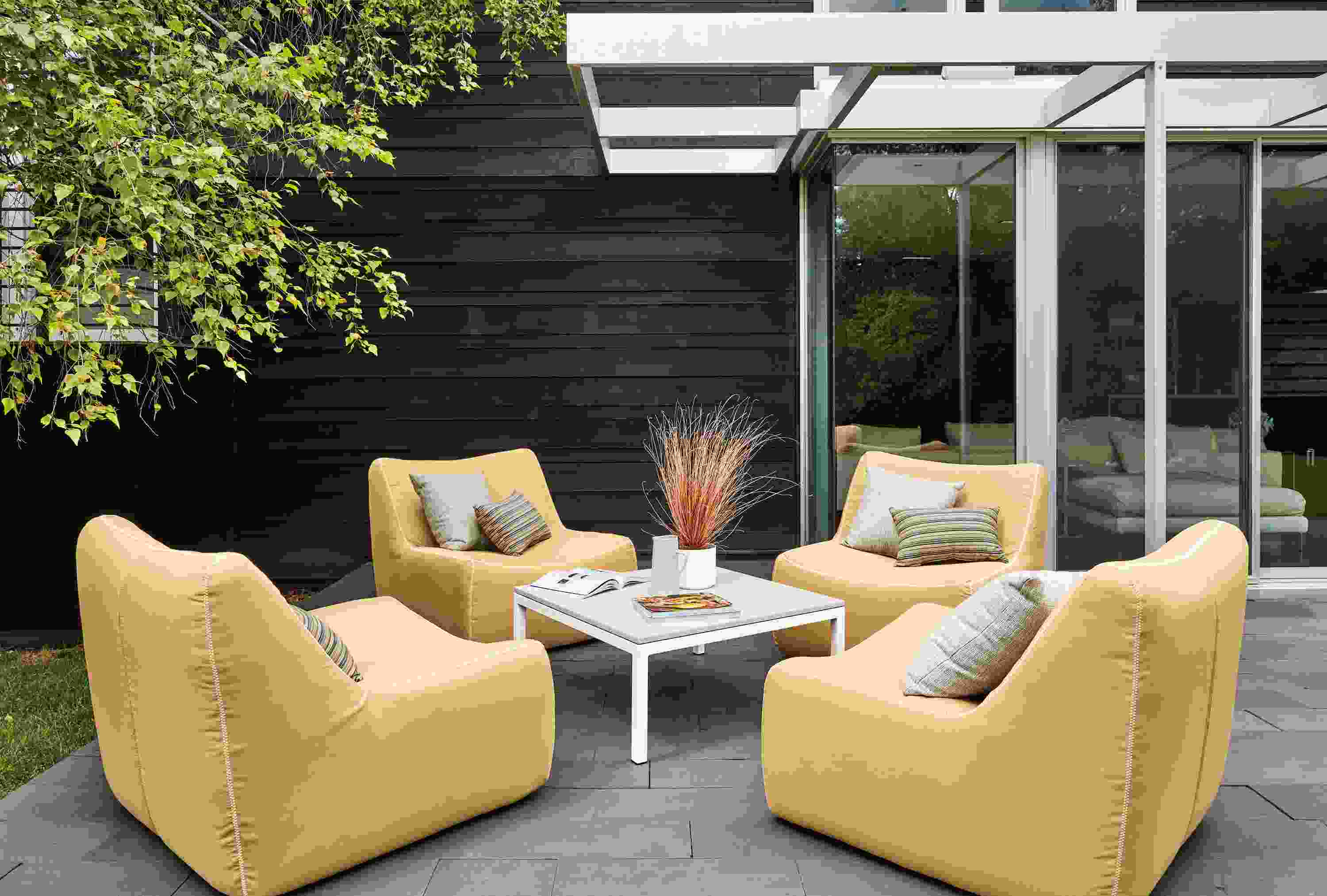 Outdoor setting with 4 Maya Swivel Chairs in Sunbrella Canvas Saffron and a Parsons 36 inch square outdoor coffee table.