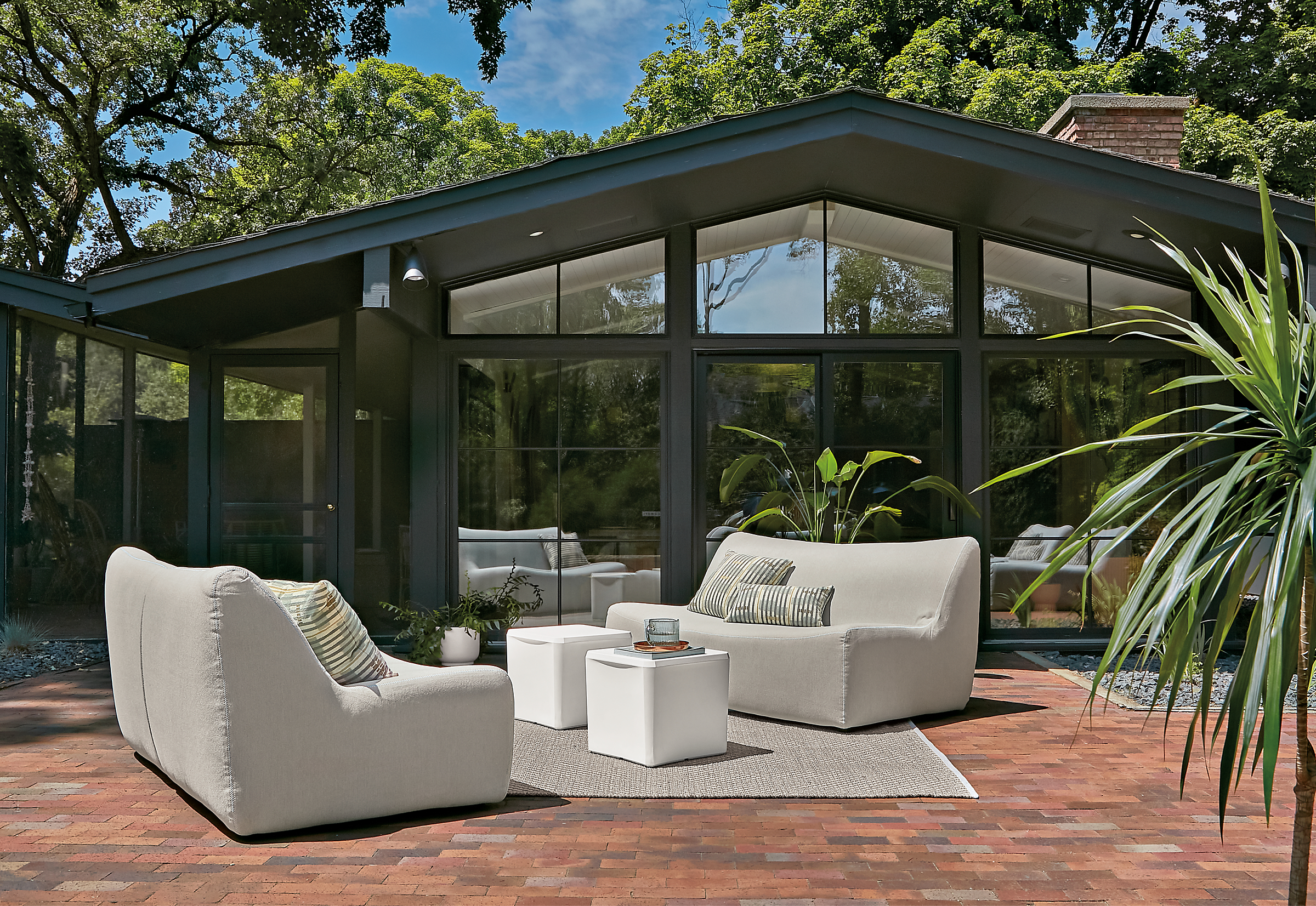 Outdoor space with two maya sofas in mist grey fabric and two cusp stools.