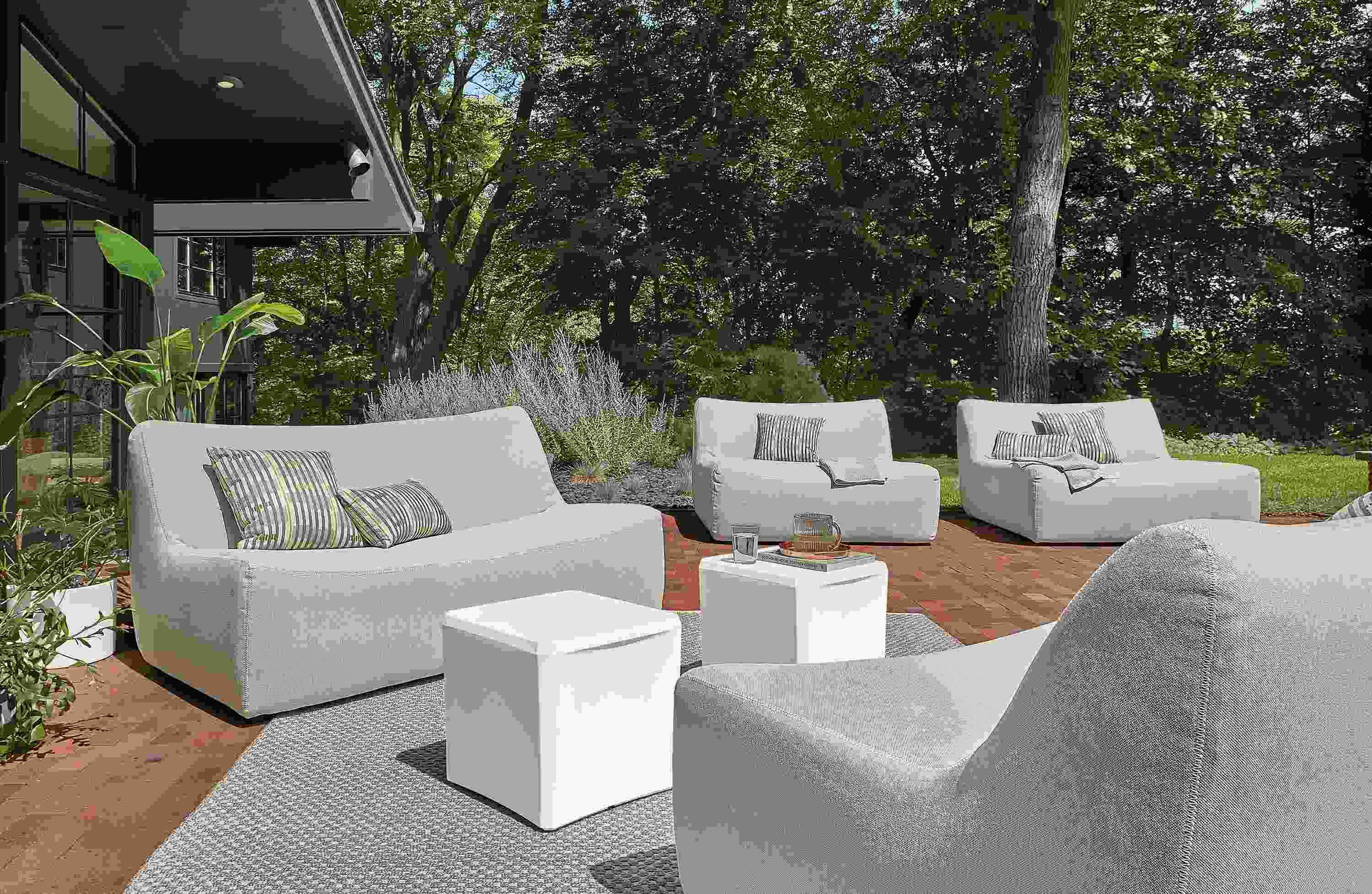Outdoor space with several large maya sofas and chaises in grey and two cusp stools.