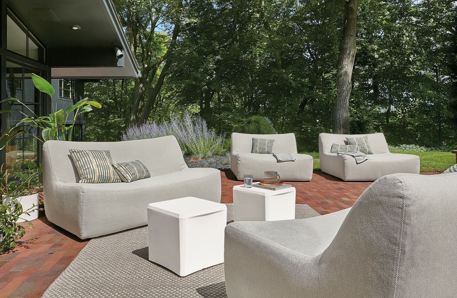 Outdoor space with several large maya sofas and chaises in grey and two cusp stools.