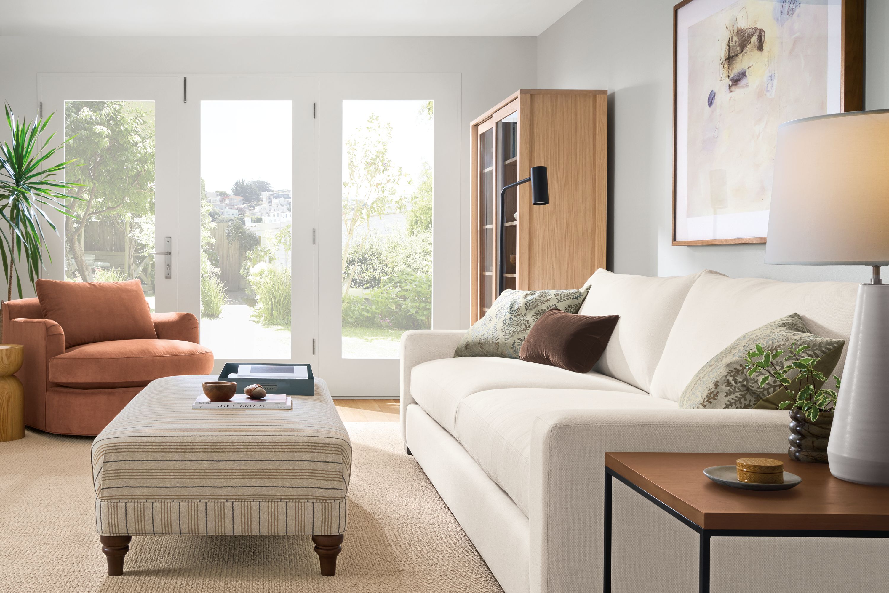 Living room with Metro deep 2-cushion sofa in Sumner Ivory, Humphrey ottoman in Prescott Natural and Flannery rug in oatmeal.