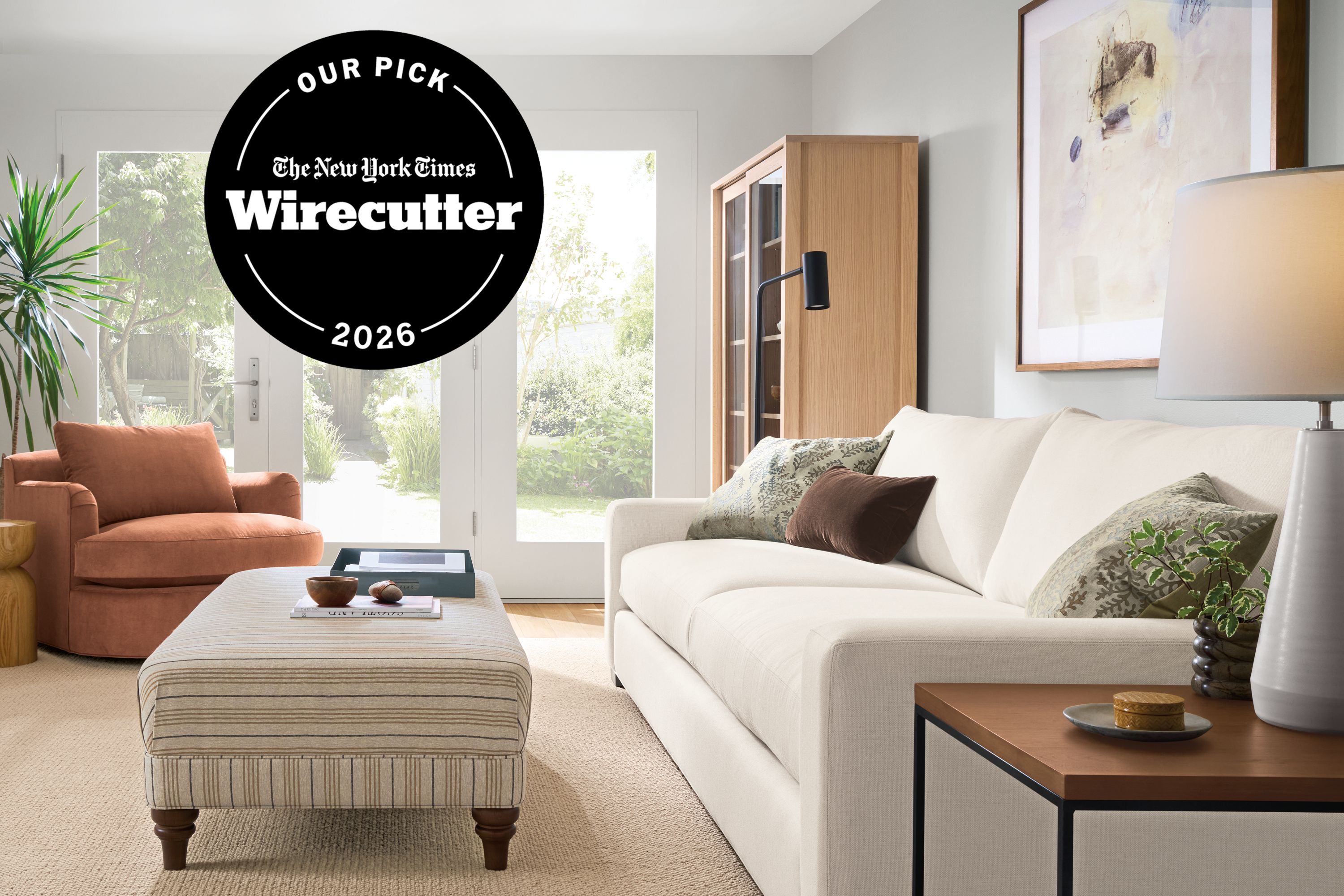 As featured in The New York Times Wirecutter 2026. Living room with Metro deep 2-cushion sofa in Sumner Ivory, Humphrey ottoman in Prescott Natural and Flannery rug in oatmeal.