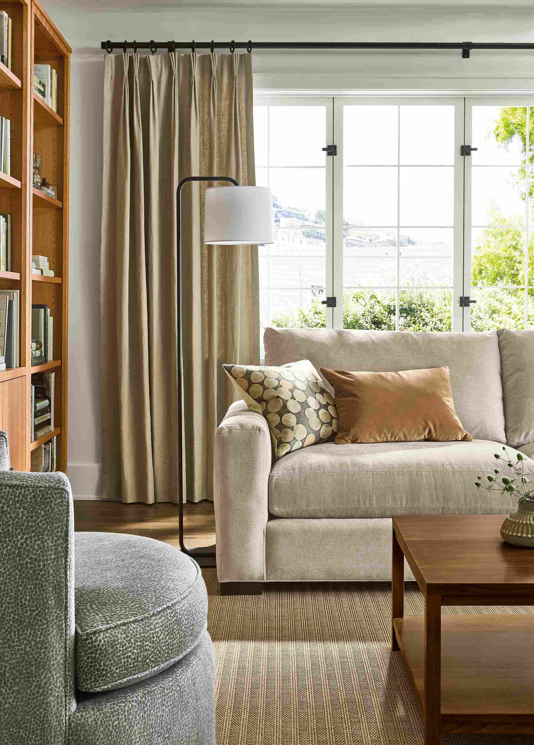 Living room with metro 88-wide sofa in mori oatmeal, otis swivel chair in faron cadet and leland 8 by 10 rug in sand.