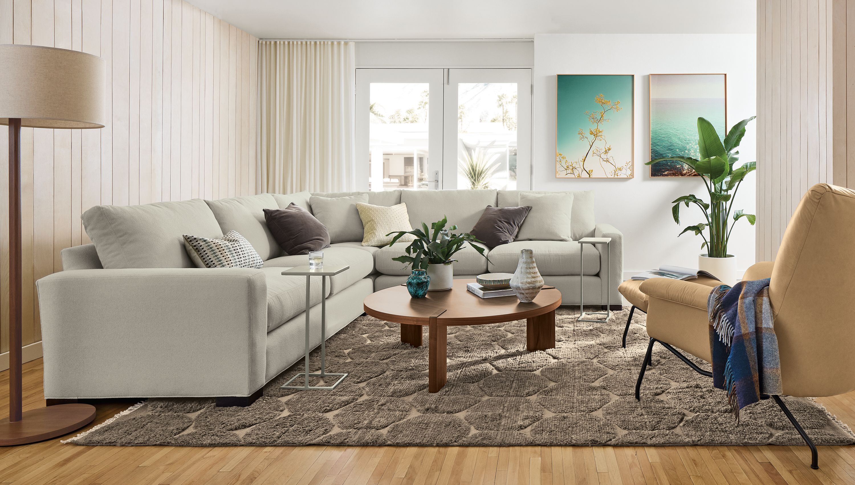 Living room with Metro 3-piece sectional in Dusk Fog,  Paris Chair and ottoman in Fiero Camel leather and Edo rug.
