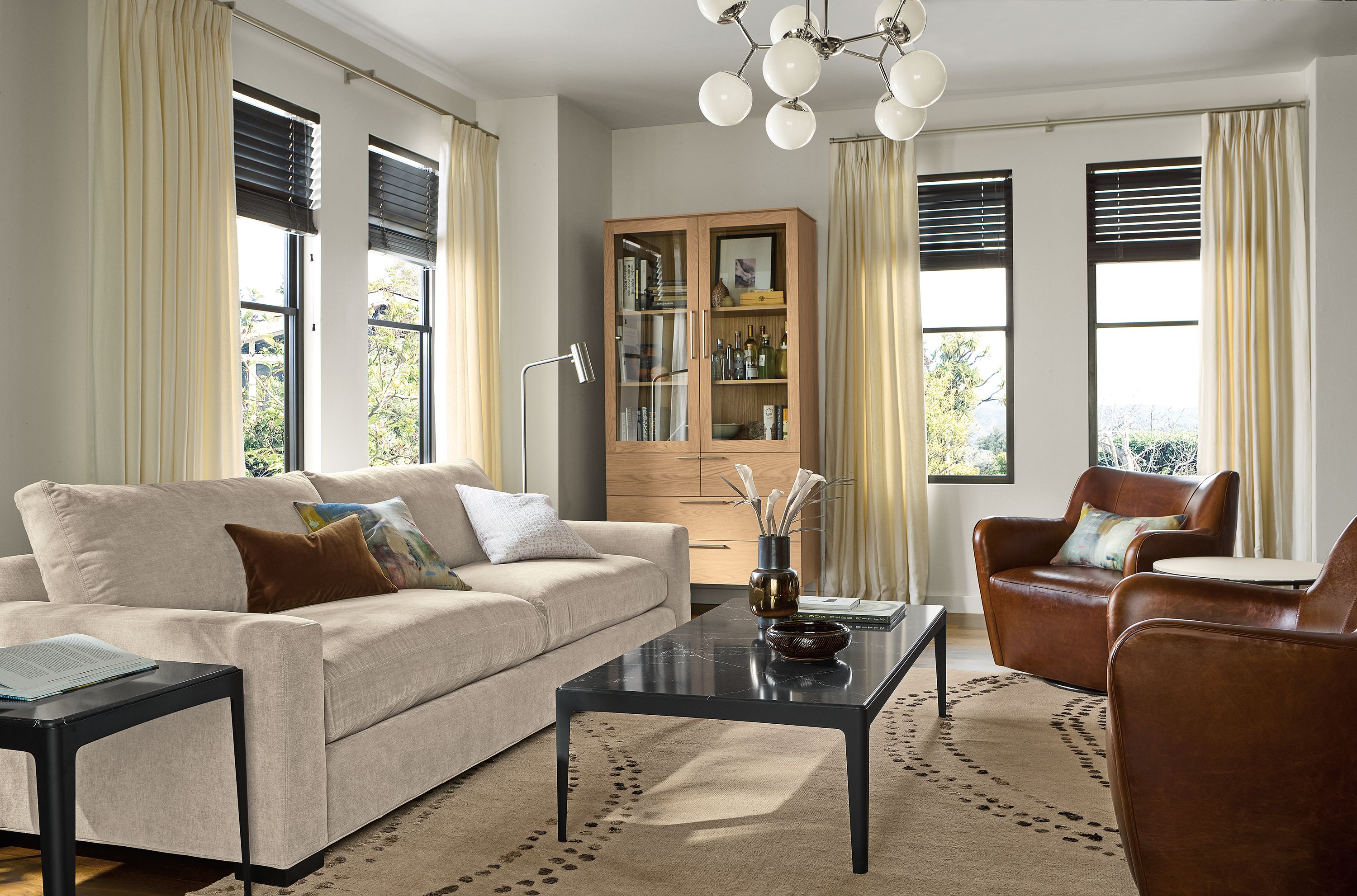 Sunny living room with Metro 108-wide sofa in Mori Oatmeal, 2 Lily swivel chairs in Vento Nutmeg leather and Sitar rug in pewter.