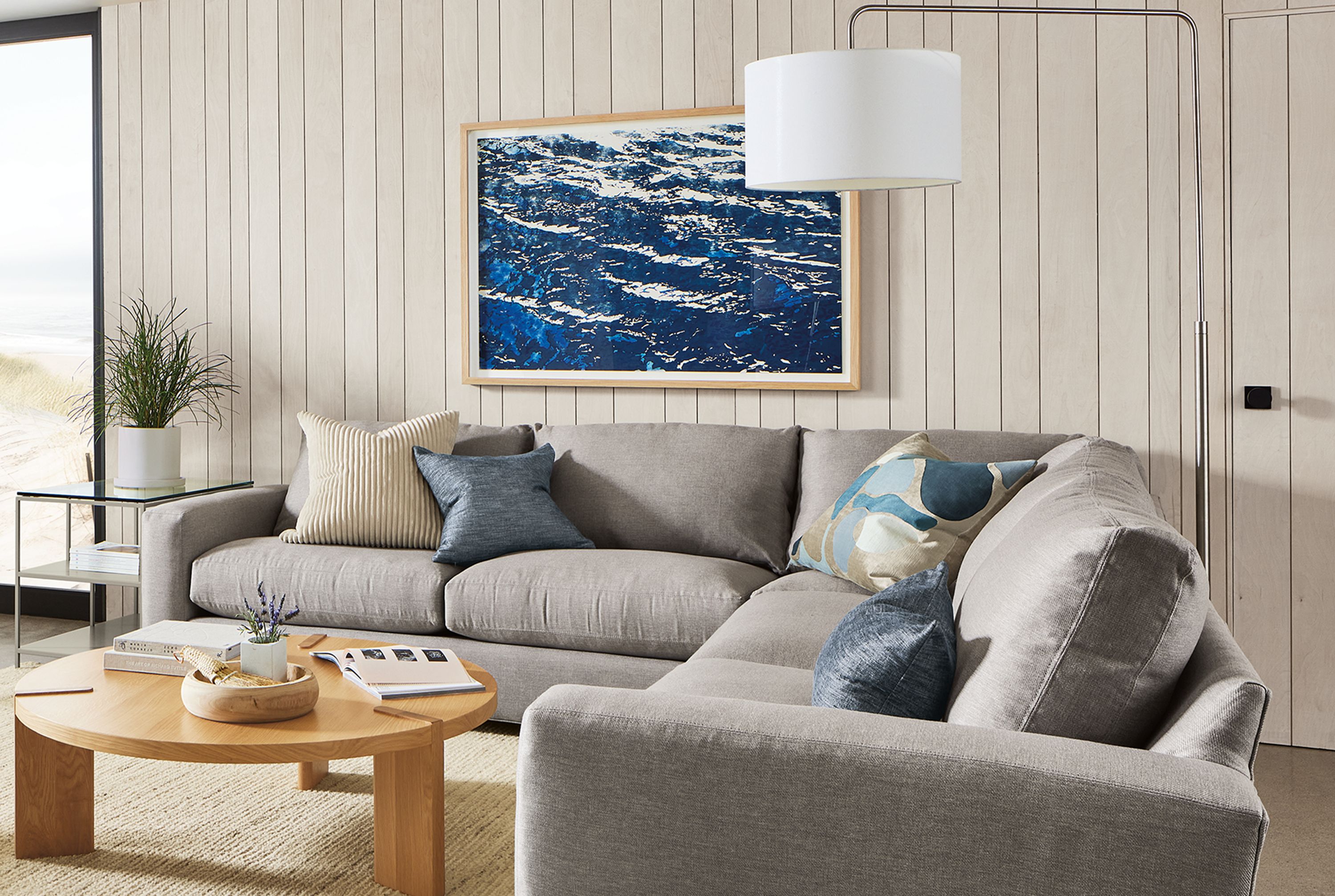 living room with metro sectional sofa in gino cement, xavier chair, lind ottoman and hanover coffee table in white oak.