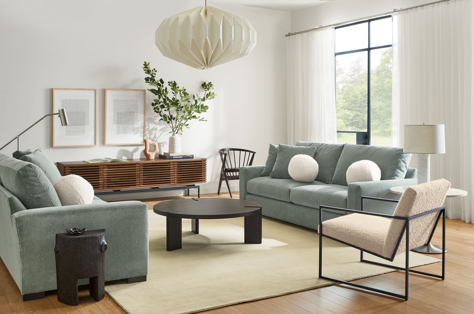 Living room setting with two Metro 88-inch Sofa in Vick lead fabric, Novato Chair in Dornick ivory fabric, Hanover 42-round Coffee Table and Casetta end table.