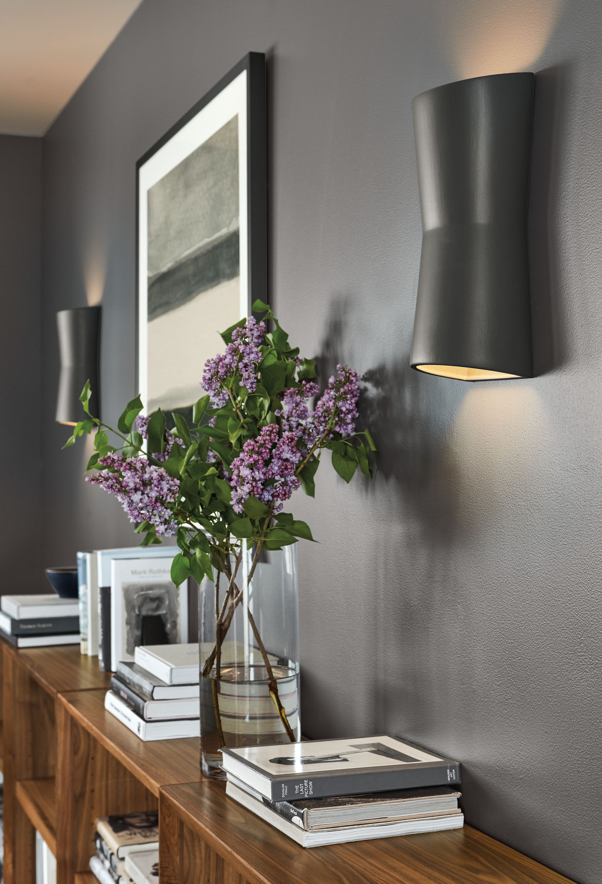 Two Mezzo wall sconces with a Valerie Francoise, Watercolor 11 wall hanging above a Lennox bookcase in Walnut.