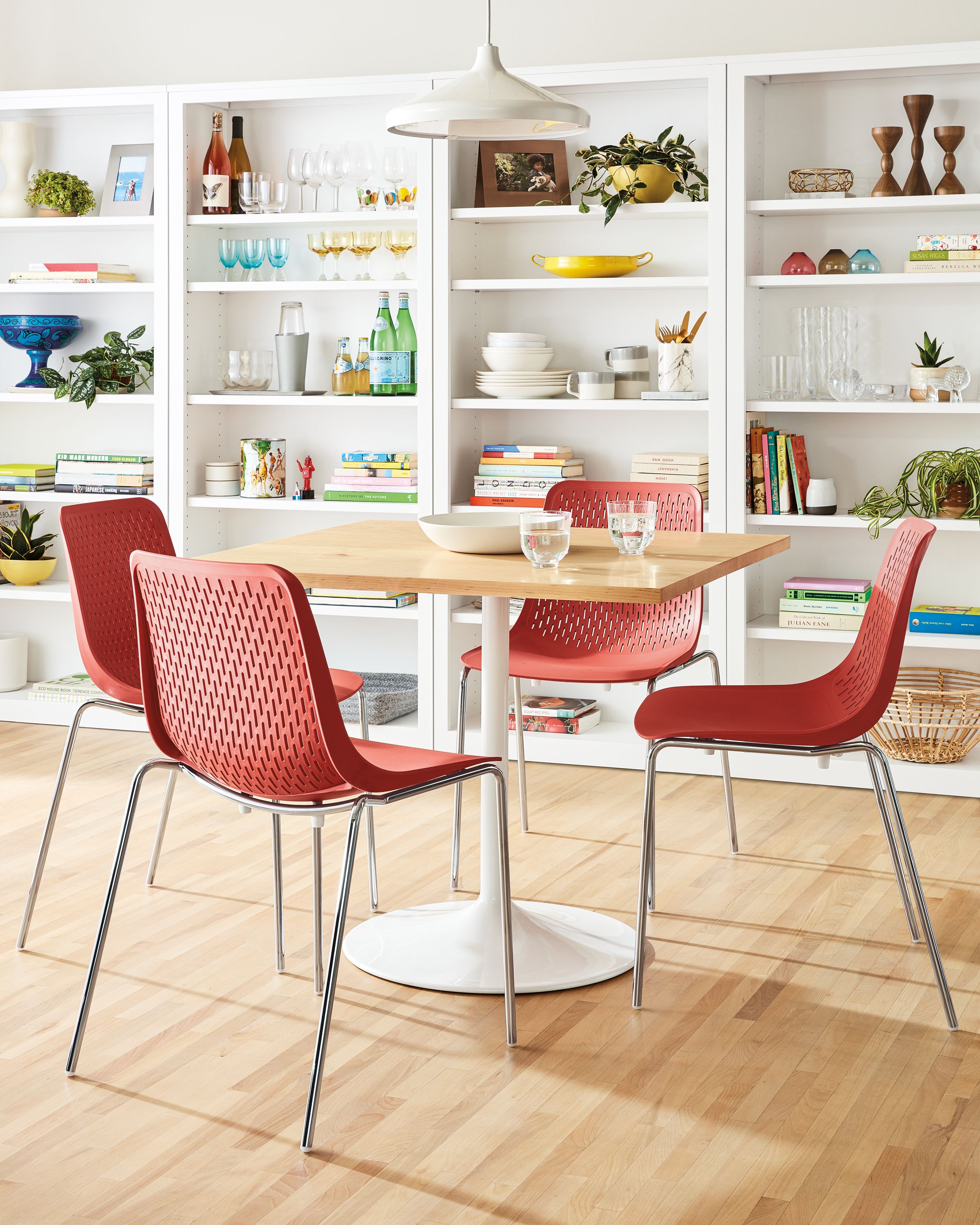 Room setting with an Aria 36-round table and 4 Mini Rain side chairs; Woodwind bookcases in white line the wall.