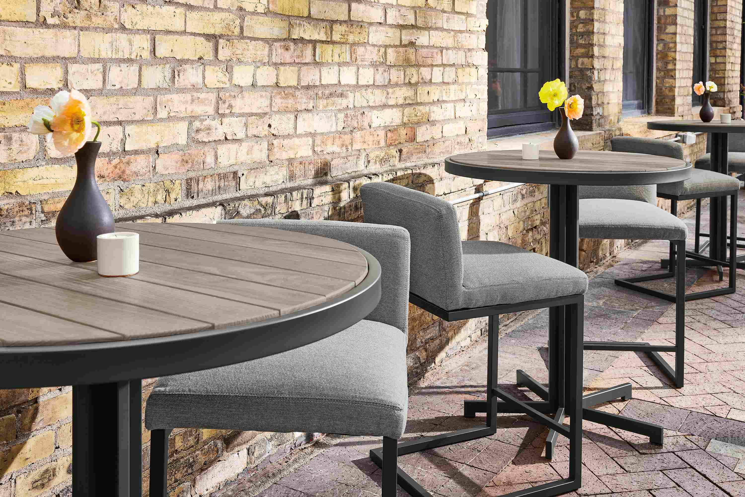 Detail of Outdoor dining space with Montego round counter tables in aged thermally modified oak and Finn counter stools in Pelham Grey.