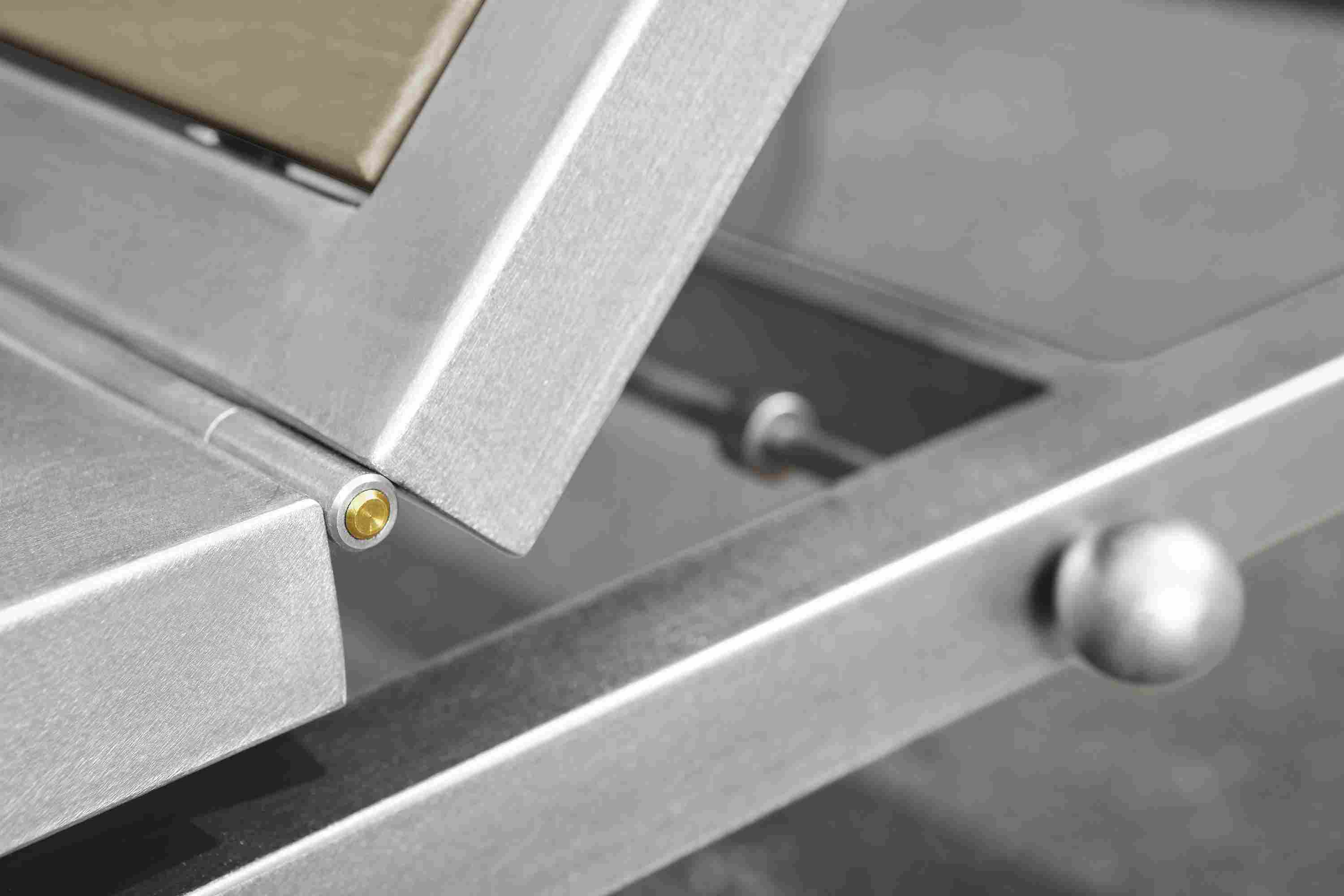 Close detail of seat hinge on a Montego chaise in stainless steel and aged thermally modified oak.