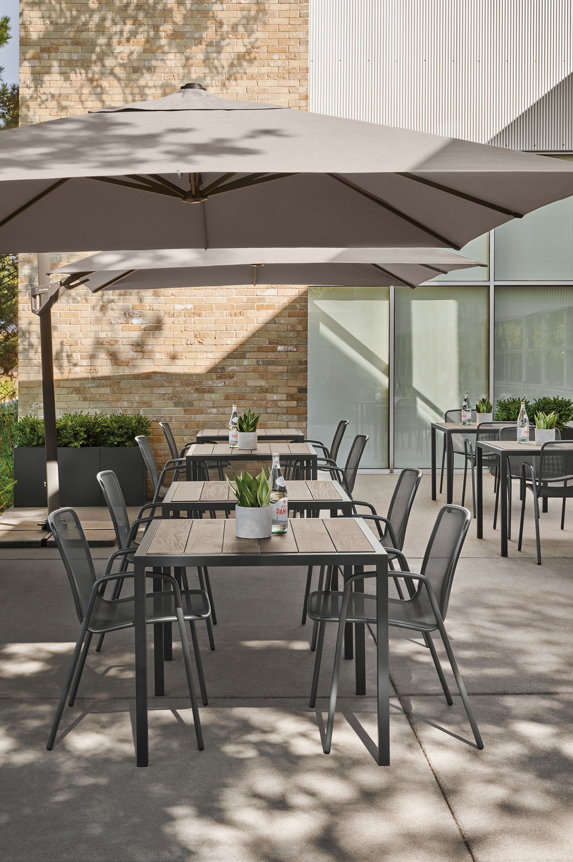 Outdoor dining area with Alto patio umbrella, Montego tables in aged thermally modified oak and Aruba chairs in graphite.