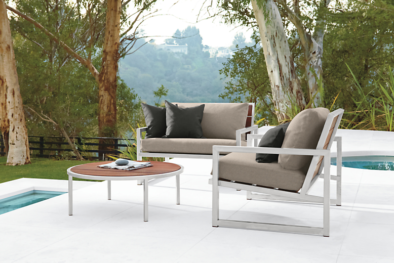 Outdoor pool setting with two Montego Lounge Chairs with Cushions and a Boyd 36-round Outdoor Ottoman.  